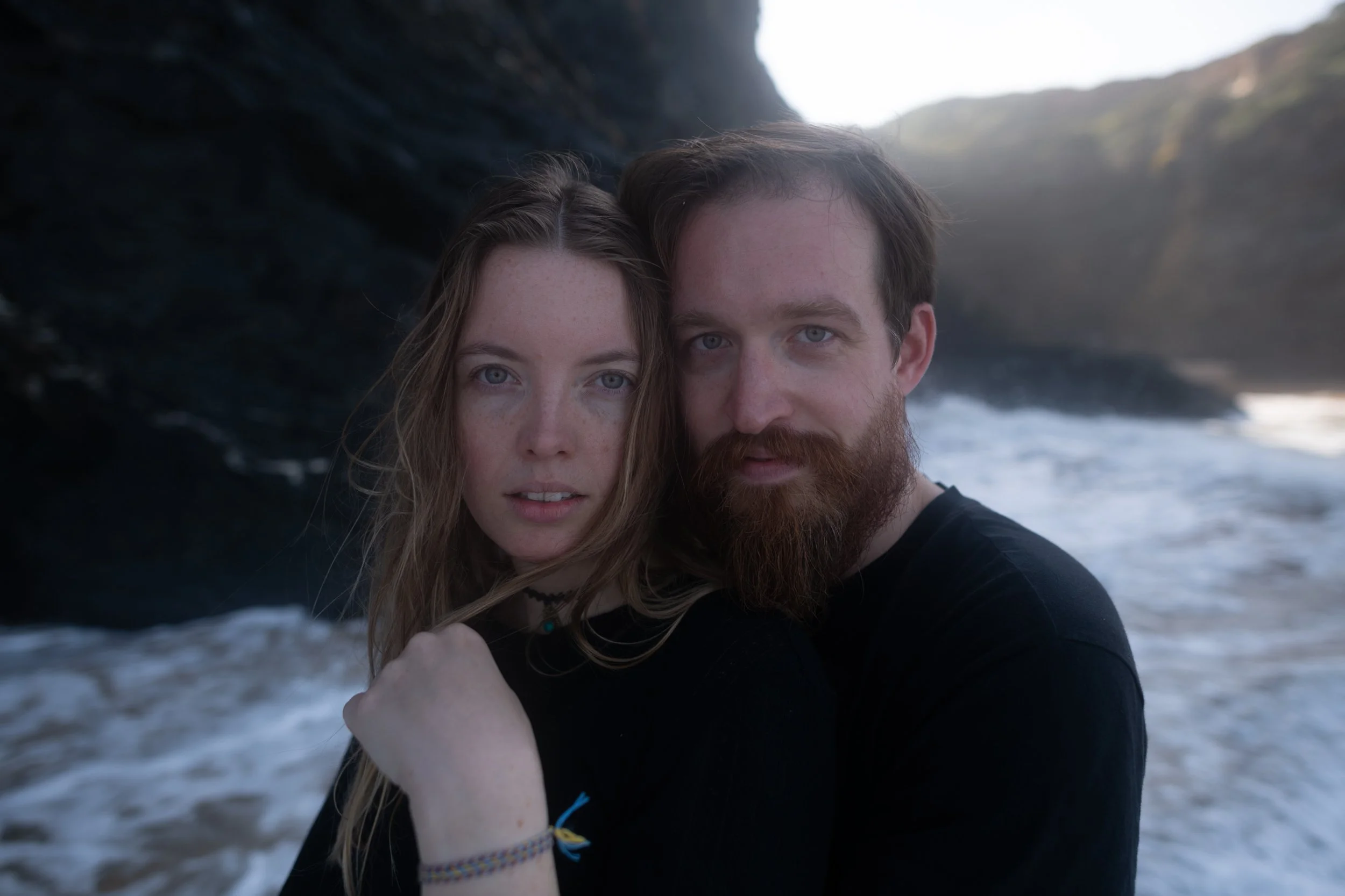Man and woman embraced in a hug with a coastal scene behind them edited with Archipelago Lightroom Presets