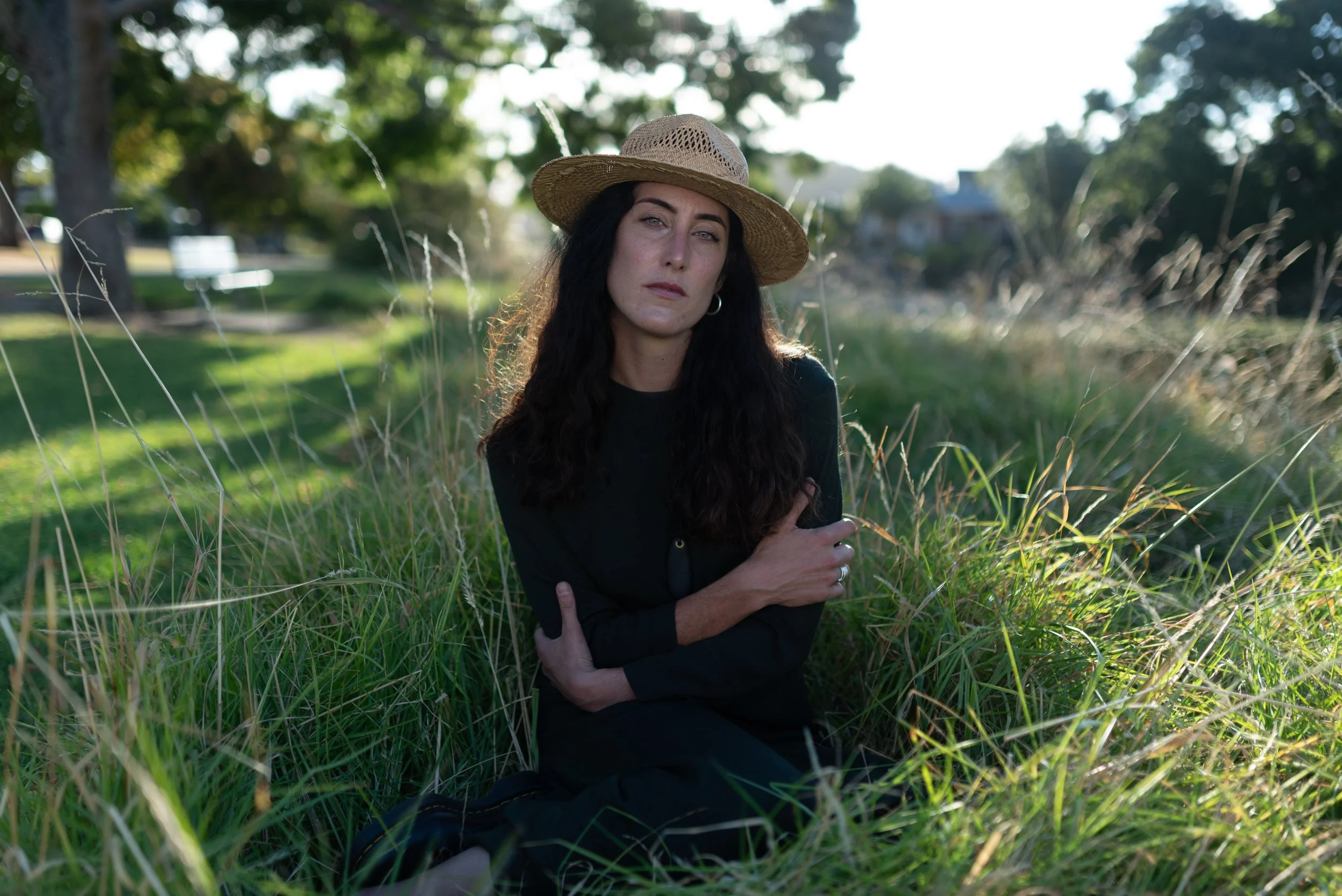 Portrait of woman sat in long grass with her hands folded over her chest edited with Archipelago Lightroom Presets