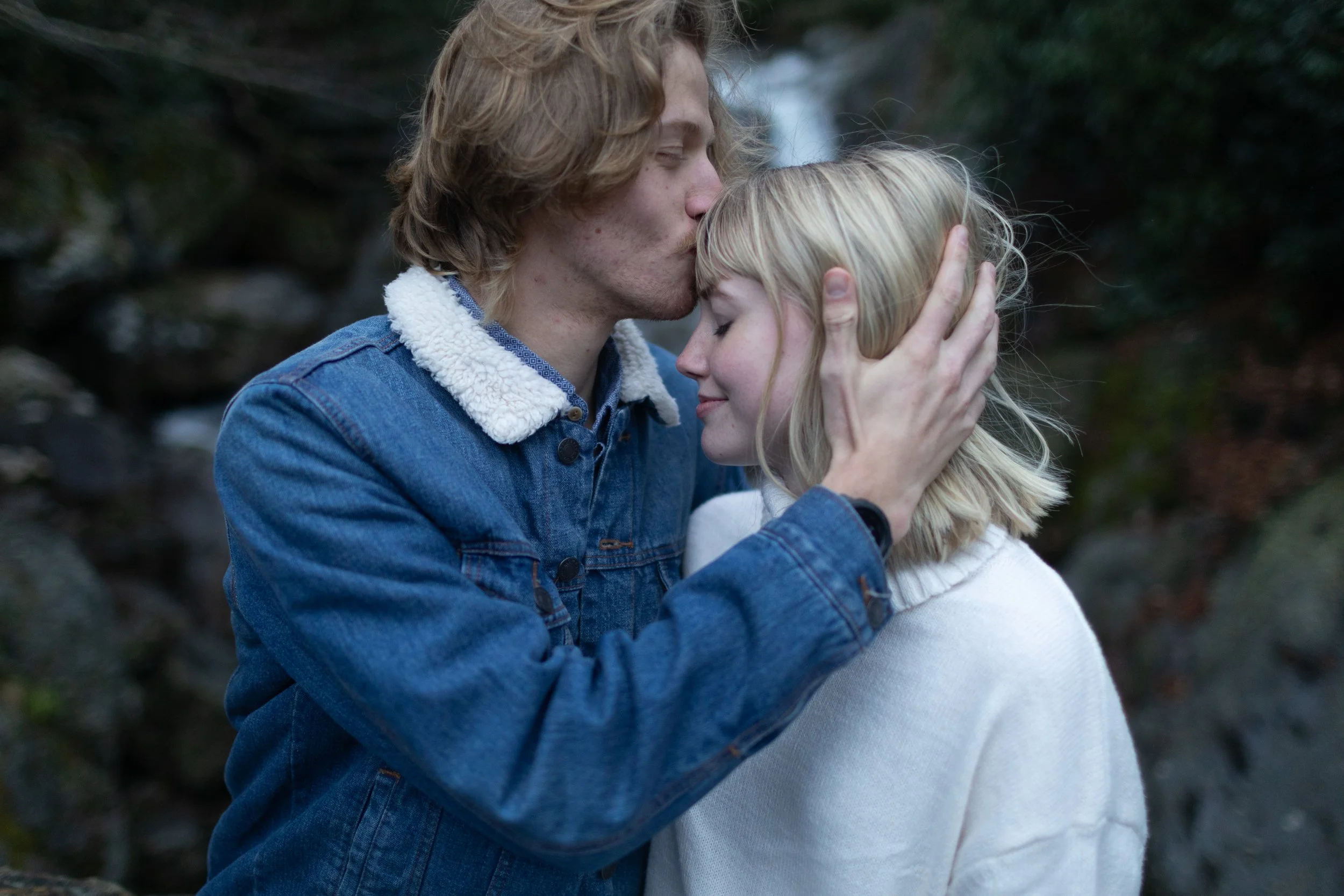 Phot of a man in a denim jacket with his hand resting against the side of a womans face and kissing her forehead edited with Archipelago Lightroom Presets