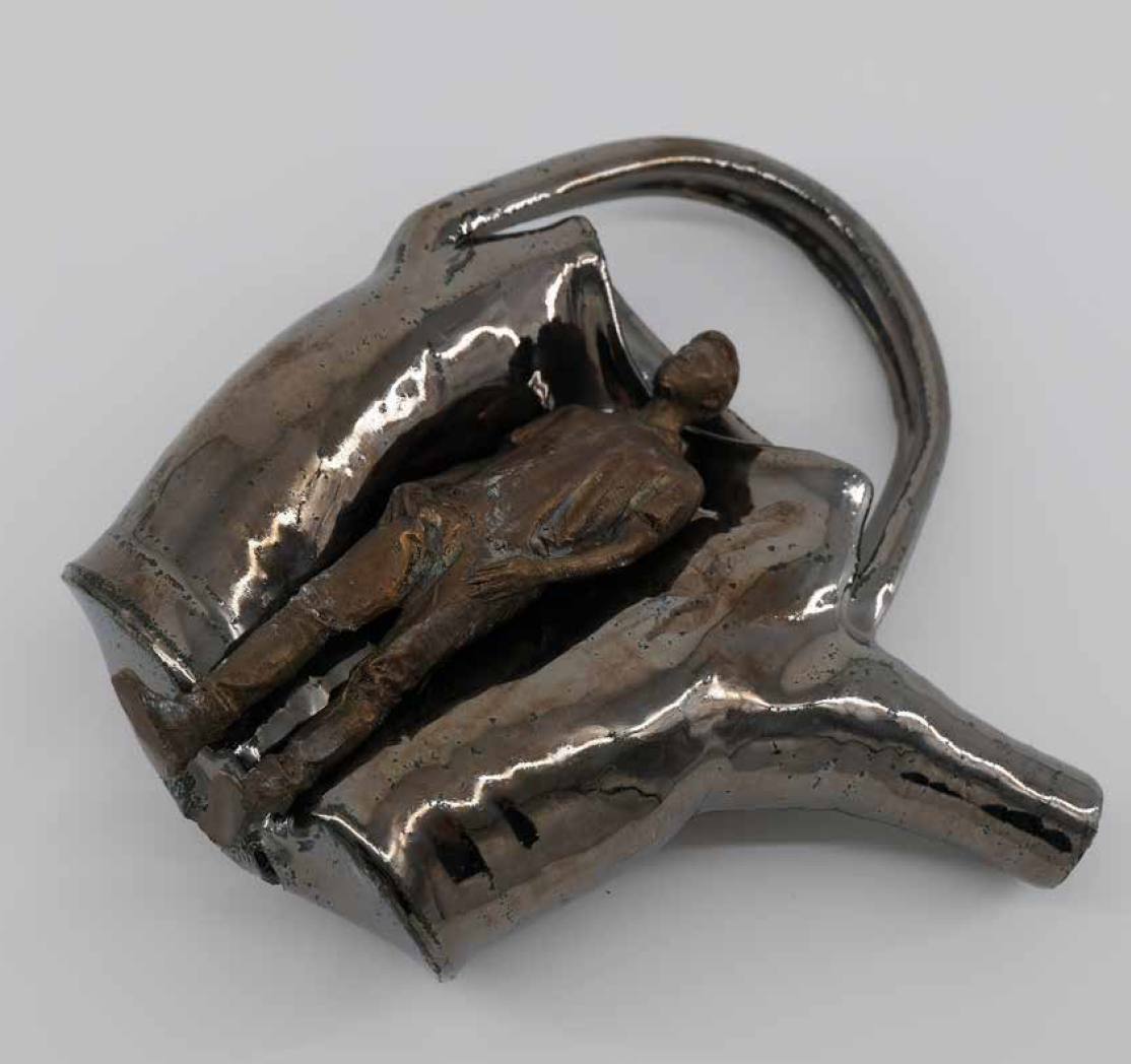 A metallic padlock with a small bronze sculpture of a firefighter in front of a fire truck on the front, reflecting light and standing out against the shiny silver surface.