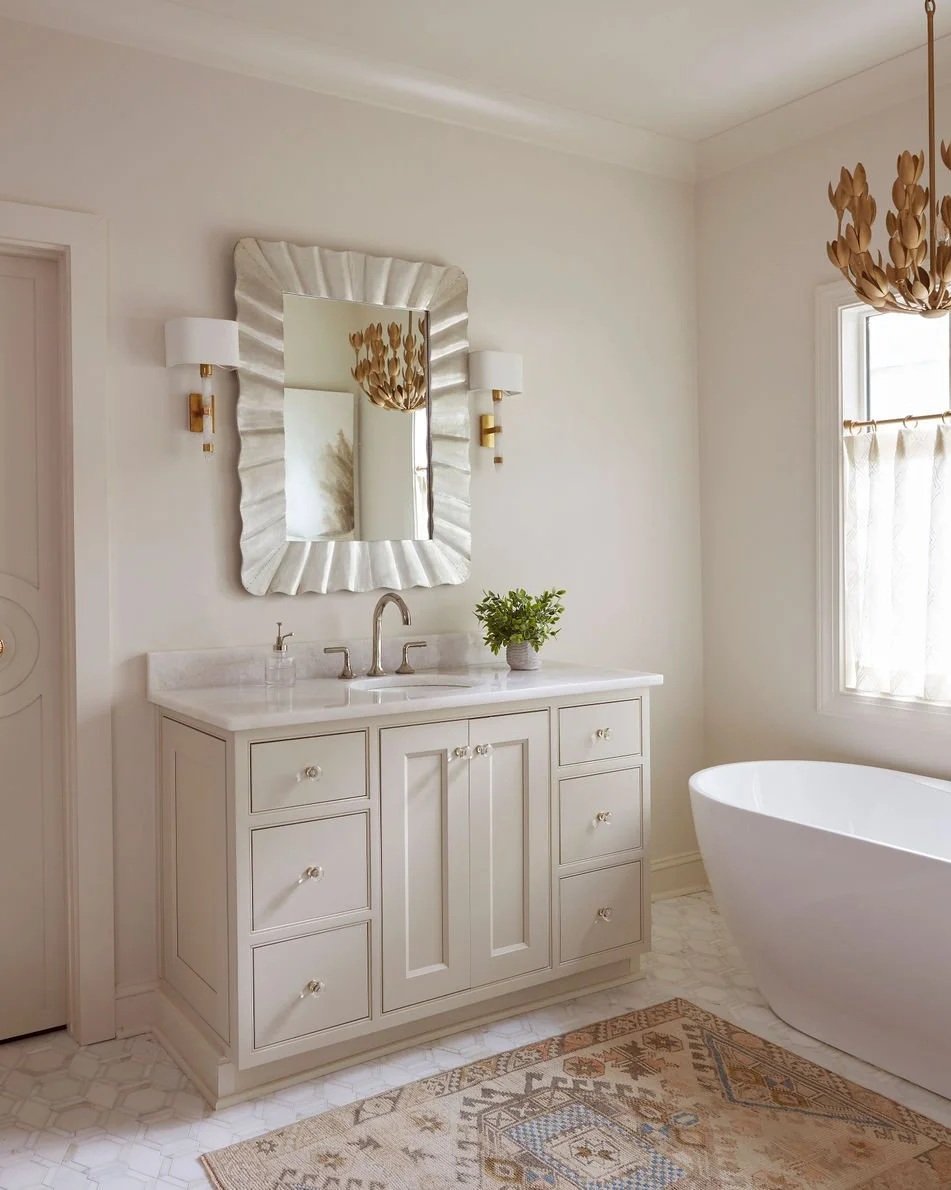 Traditional bathroom featuring a furniture-style vanity, marble-look countertop, decorative mirror, and freestanding soaking tub designed by Toulmin Kitchen & Bath in Tuscaloosa, Alabama.