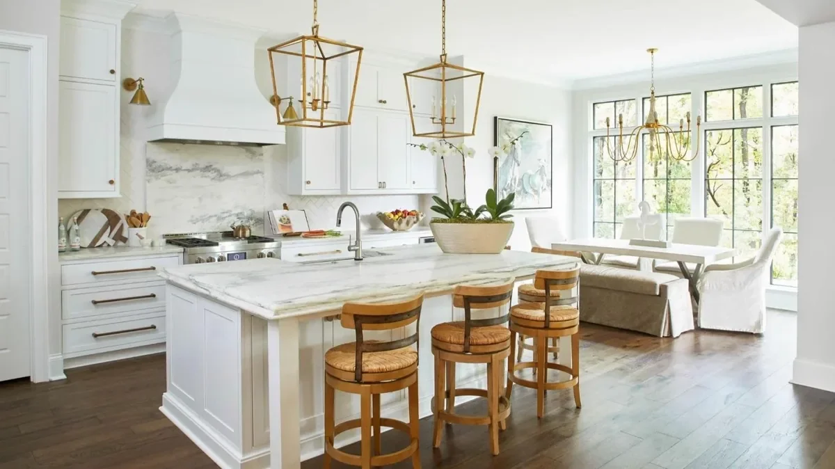 White kitchen remodel featuring marble backsplash, gold hardware, custom cabinetry, and a large island.