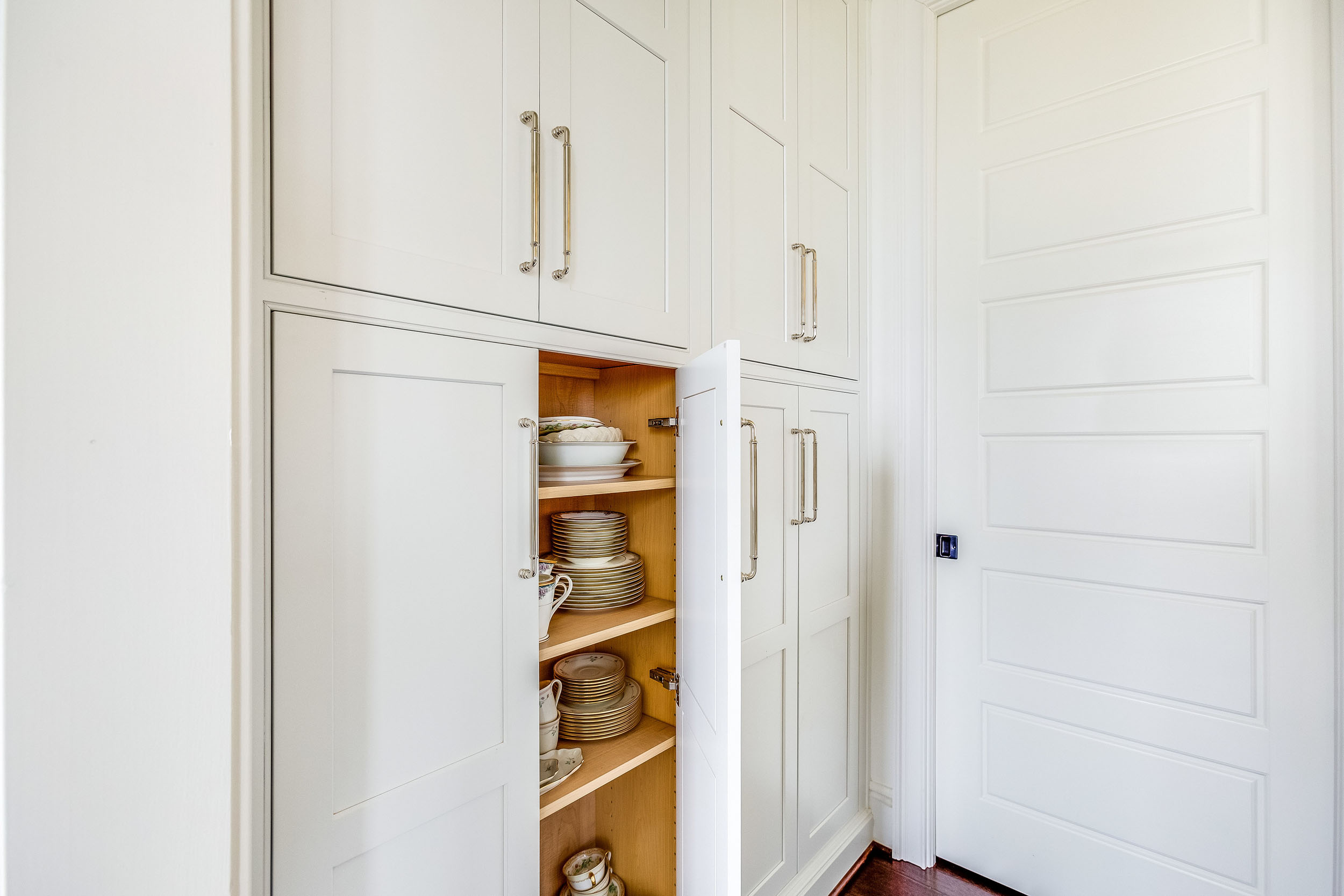 A white kitchen cabinet design with oversized nickel handles.