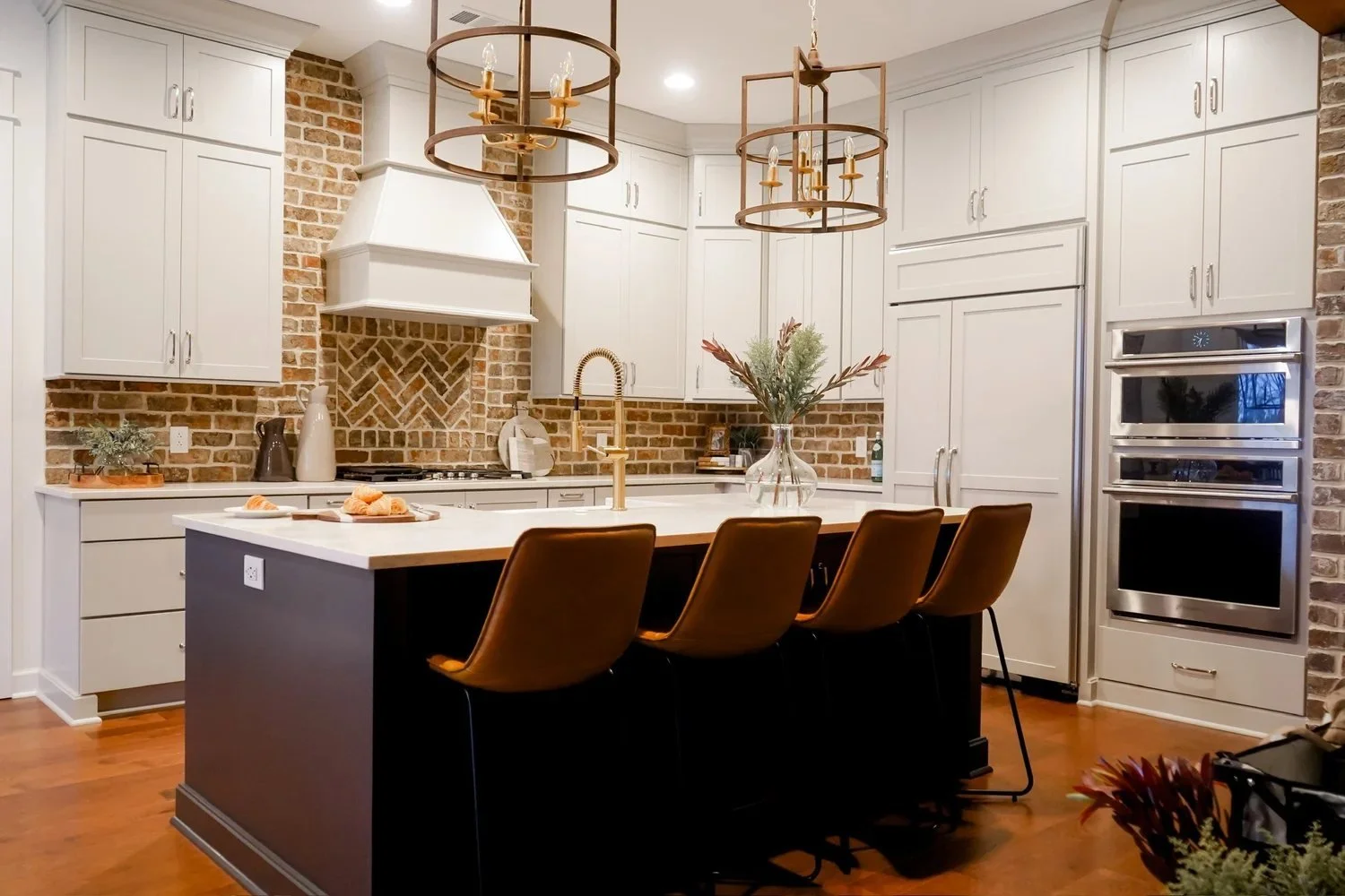 Remodeled Tuscaloosa kitchen with white custom cabinetry, large island, brick backsplash and built-in appliances.