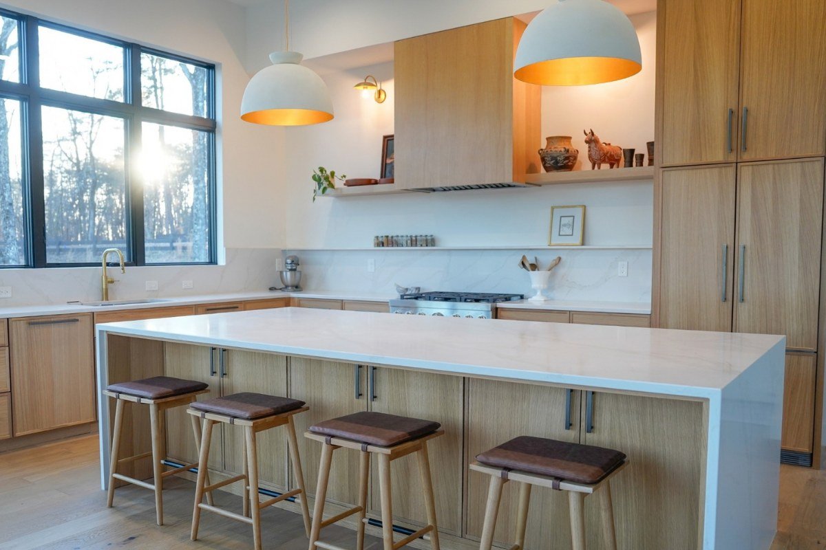 Warm wood kitchen with full-splash stone backsplash, slim backsplash ledge and large waterfall island