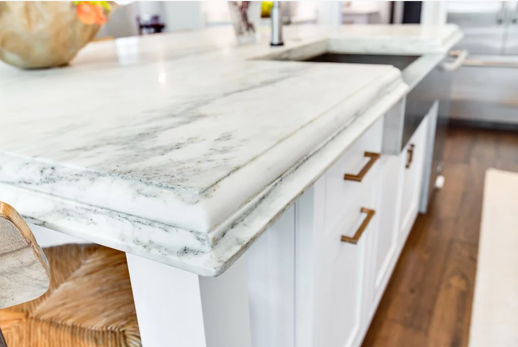 Close-up of a marble countertop with a decorative ogee edge profile and built-up thickness, highlighting layered detailing and veining.
