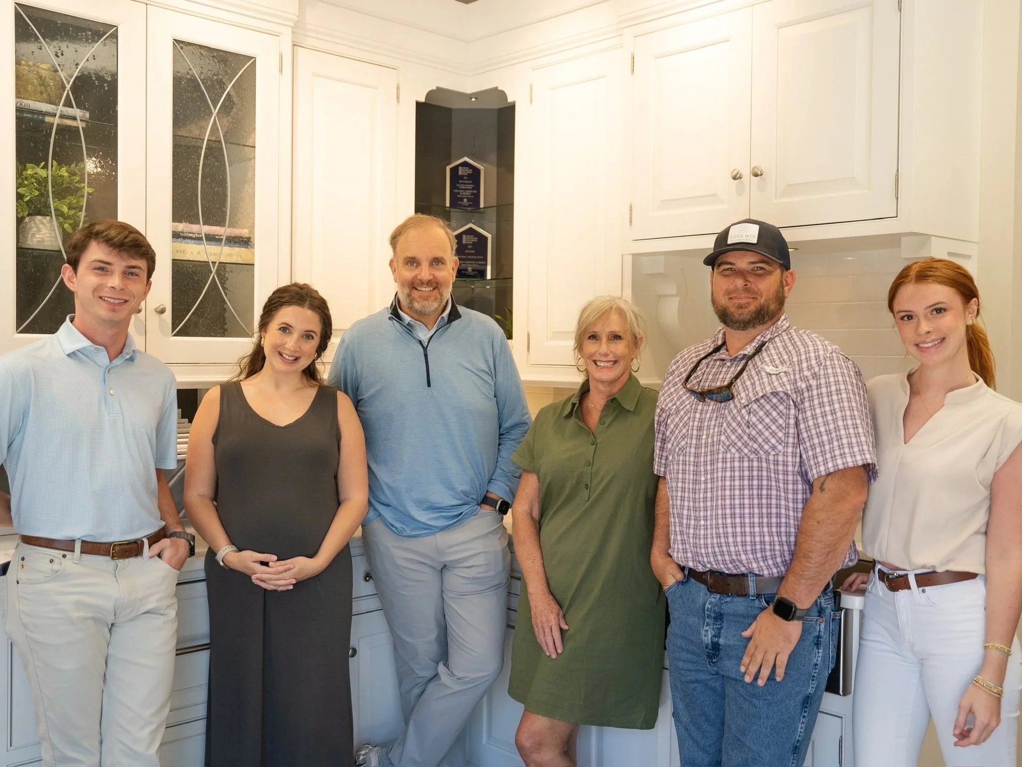 Toulmin Kitchen & Bath team gathered in their Tuscaloosa showroom, collaborating and reviewing design materials in a bright, modern space