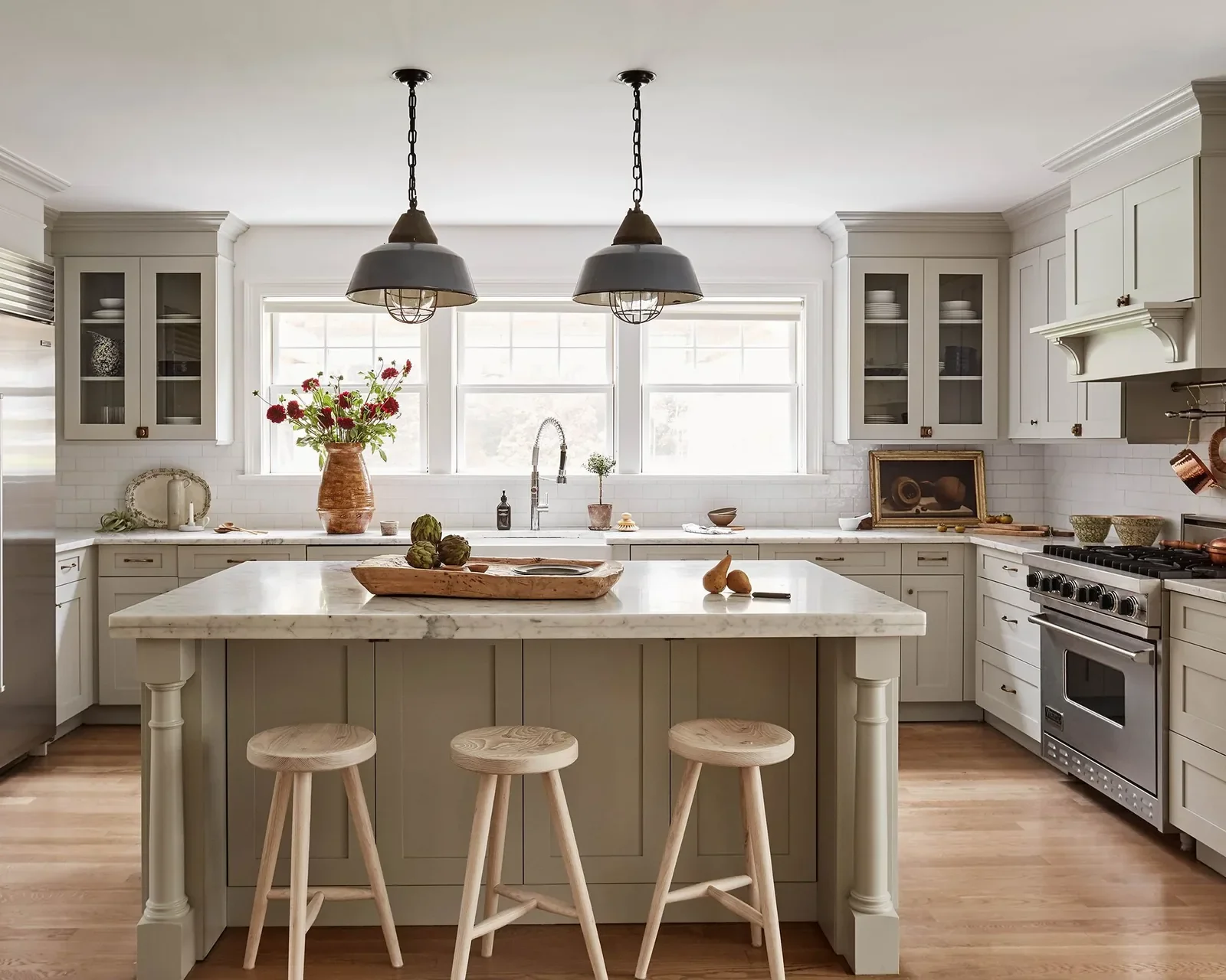 Coastal Grandmother kitchen design featuring sage green custom cabinetry, marble island, and brass lighting in an Alabama home.