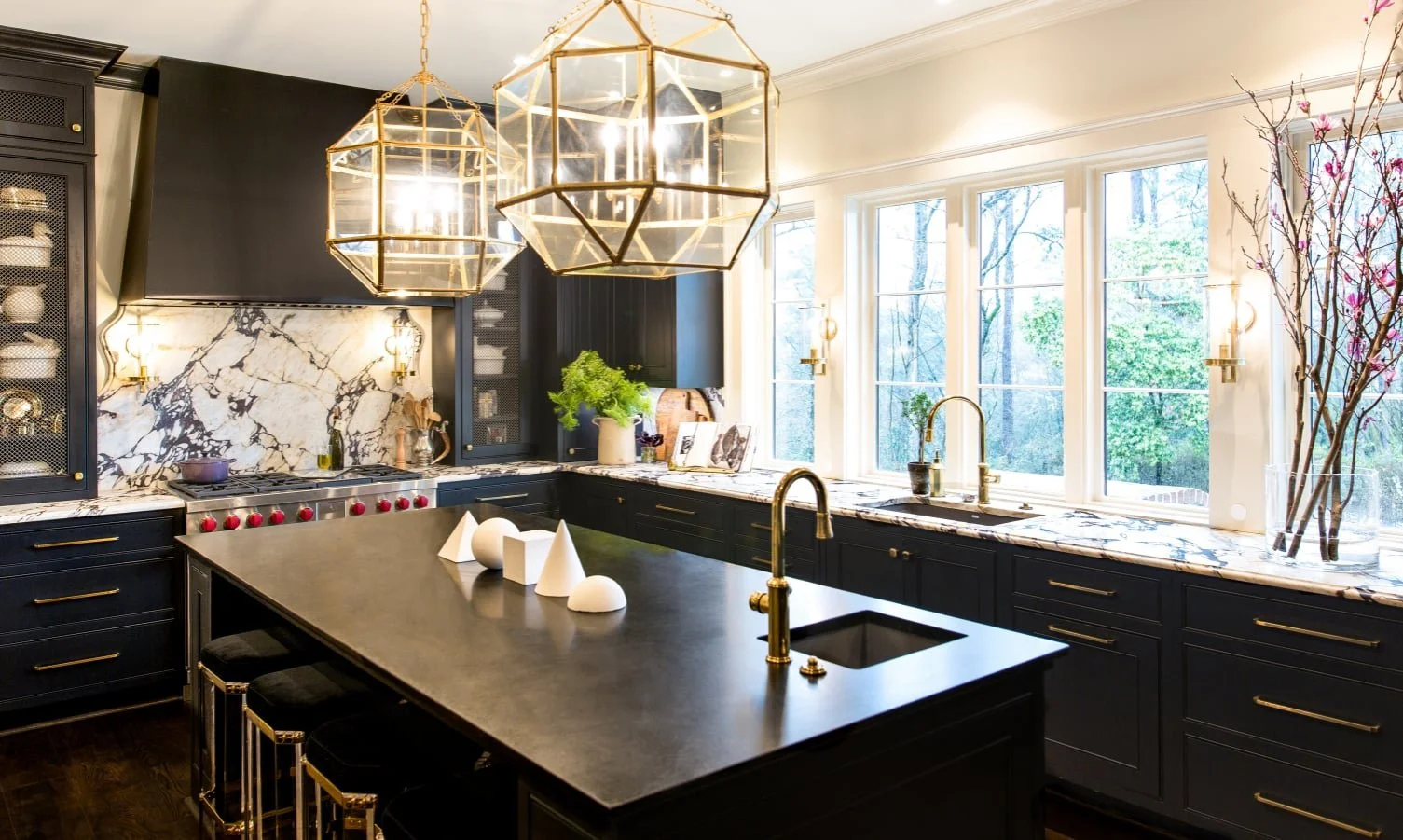 Black Cantley & Toulmin custom kitchen cabinetry with brass hardware, large island, statement lighting, and dramatic stone countertops.