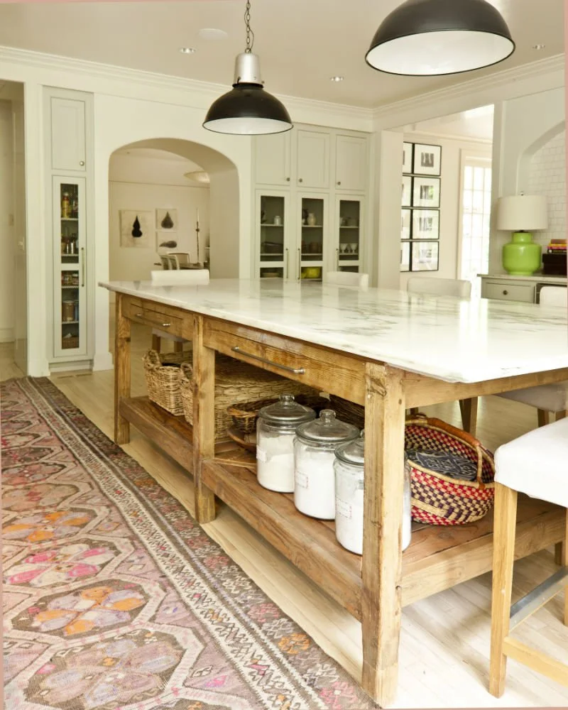 Furniture-style wood kitchen island with open shelving, baskets and marble countertop