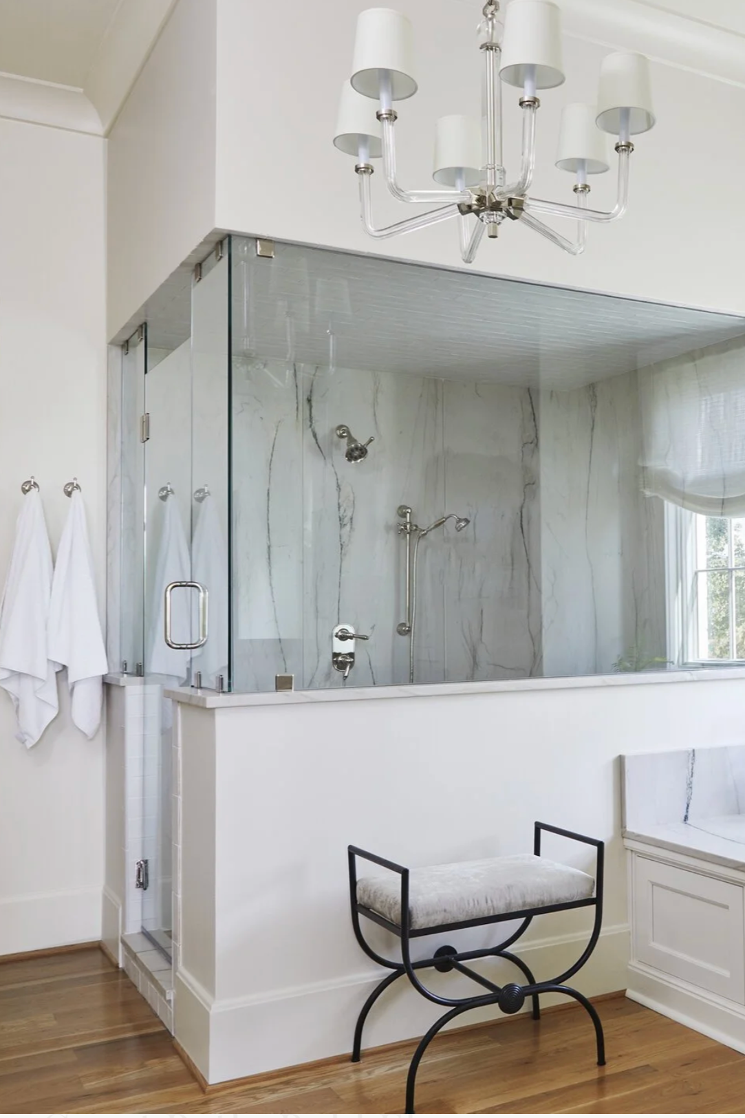 Transitional luxury bathroom featuring a glass-enclosed shower with marble-look tile, statement chandelier, and refined finishes designed by Toulmin Kitchen & Bath in Tuscaloosa, Alabama.