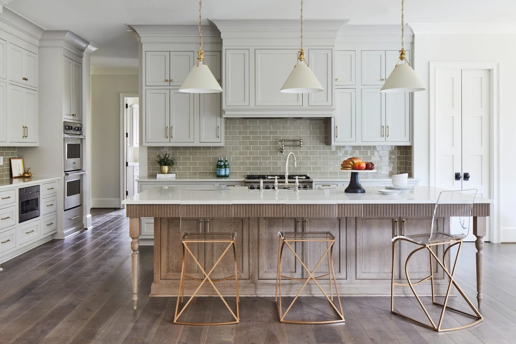 A kitchen island  with reeded millwork detailing, elegantly turned legs, and rift-sawn white oak create a furniture-inspired focal point that brings warmth, texture, and timeless character to the heart of the home.