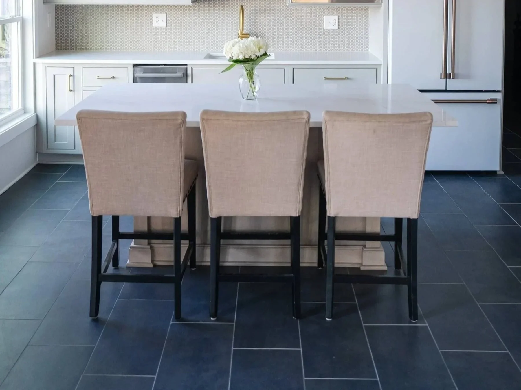 Tuscaloosa-area kitchen with dark tile flooring, white cabinetry, and a large island with seating.