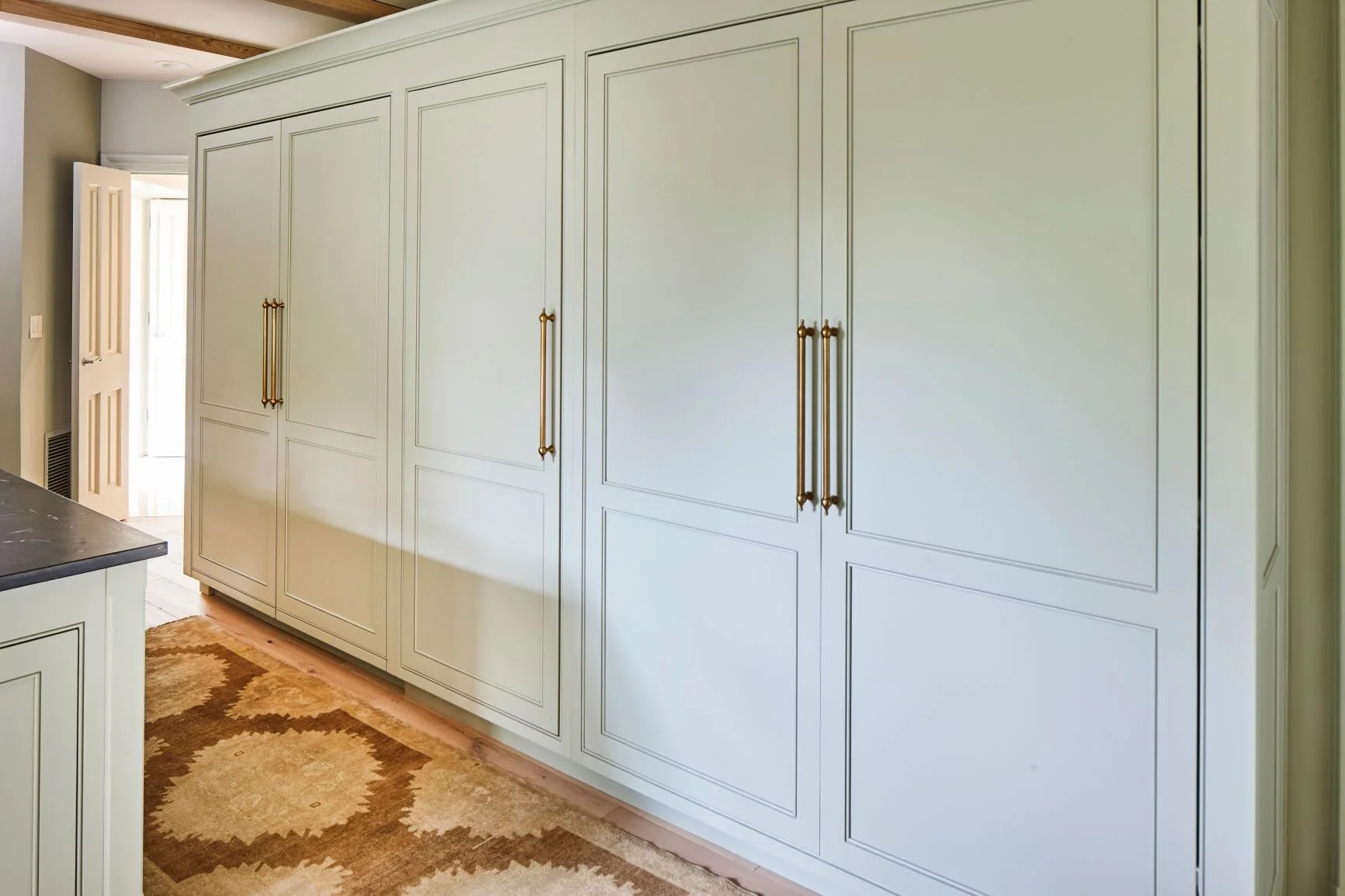 Integrated refrigerator concealed behind custom cabinet-paneled doors with brass hardware in a Birmingham kitchen.