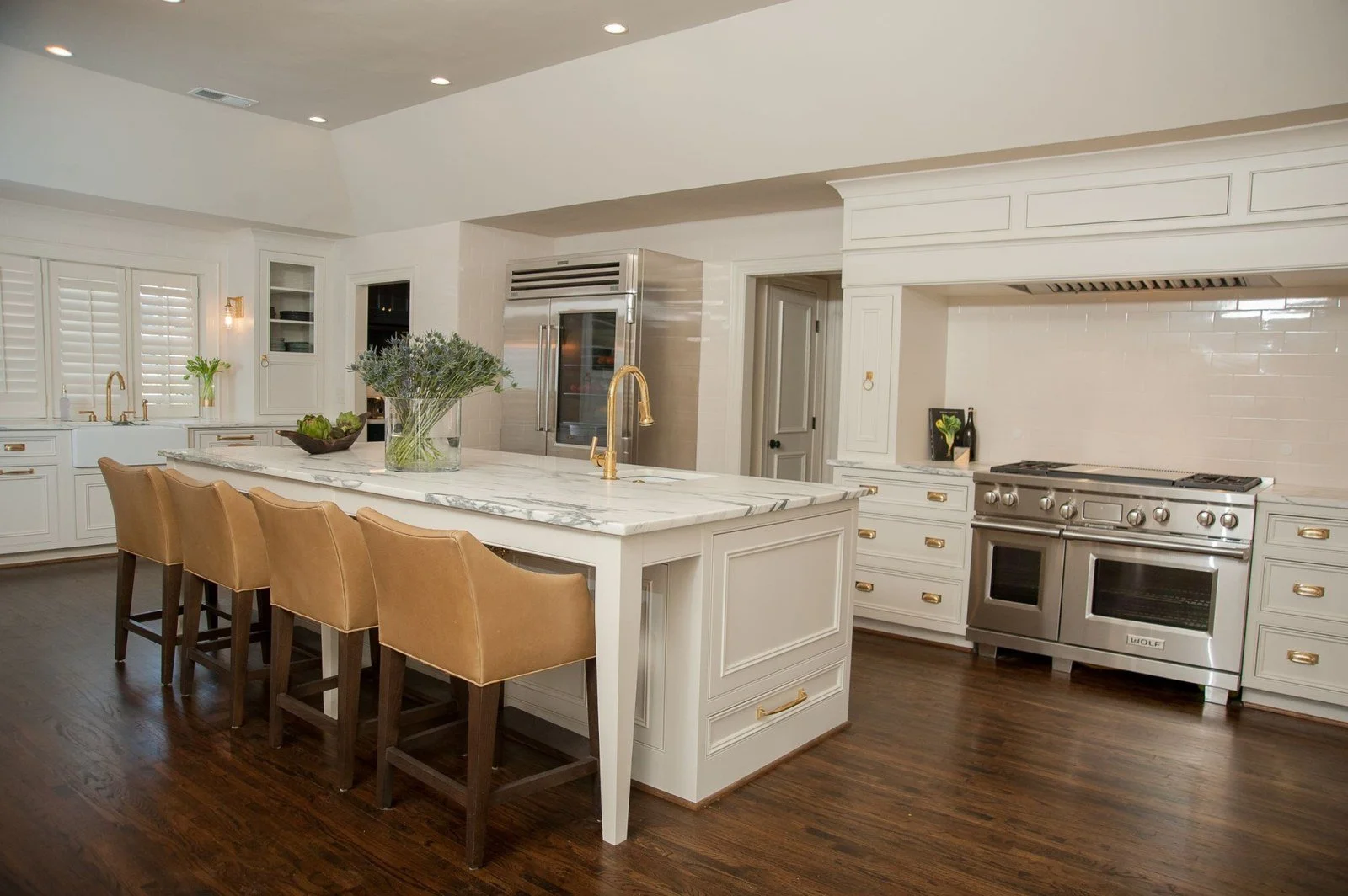 Custom kitchen island with inset cabinetry, deep storage drawers, brass hardware, and a dark stone countertop.