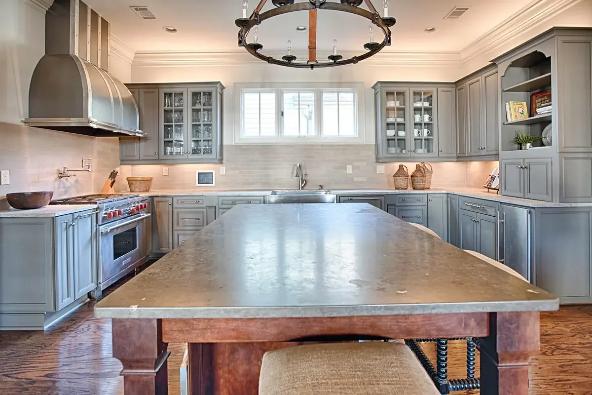Modern kitchen remodel featuring gray custom cabinetry, a large quartz kitchen island, and premium countertops designed by Toulmin Kitchen & Bath in Tuscaloosa, Alabama.