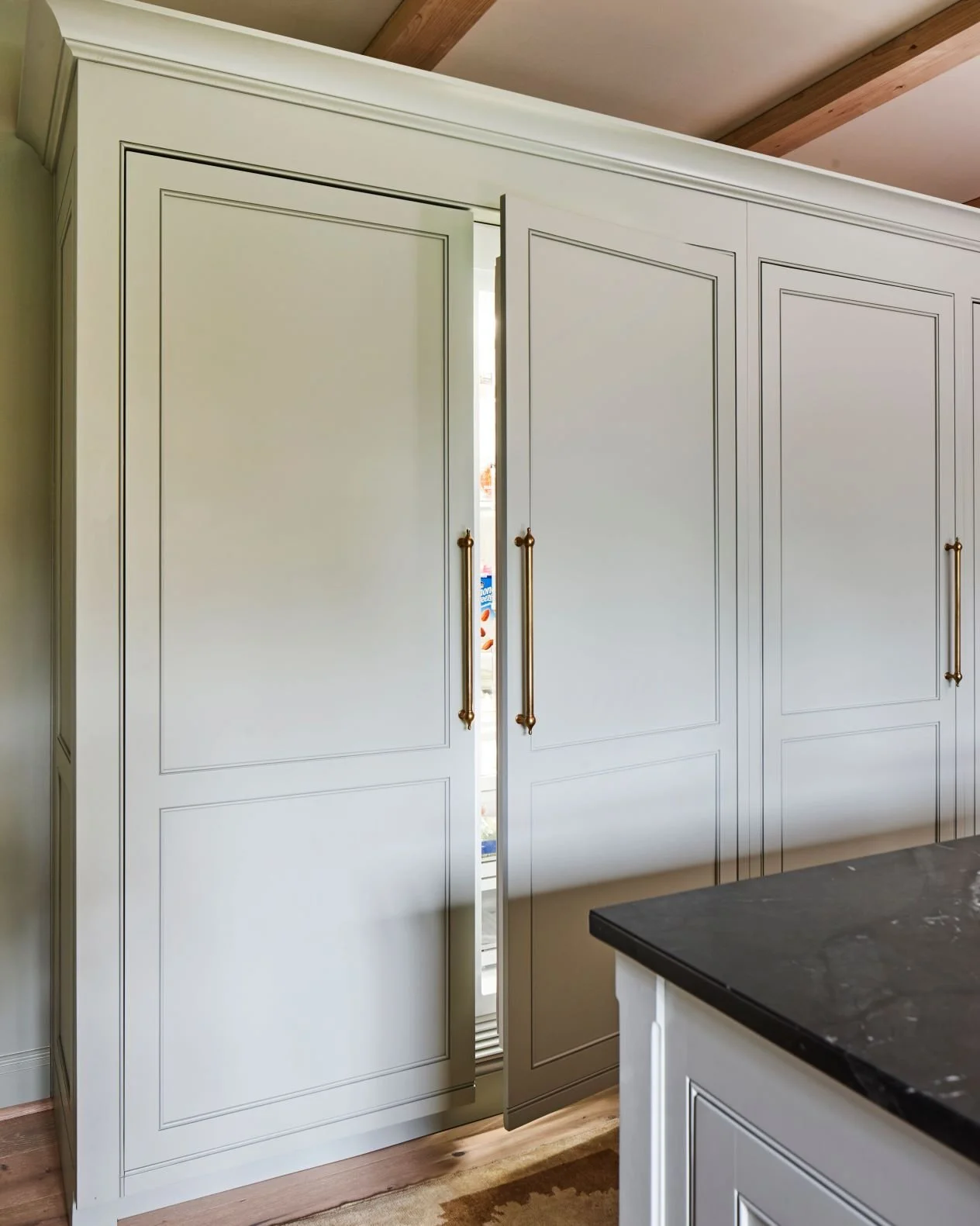Custom kitchen cabinetry with integrated paneled refrigerator doors, brass hardware, and inset cabinet detailing in a luxury Alabama kitchen design.