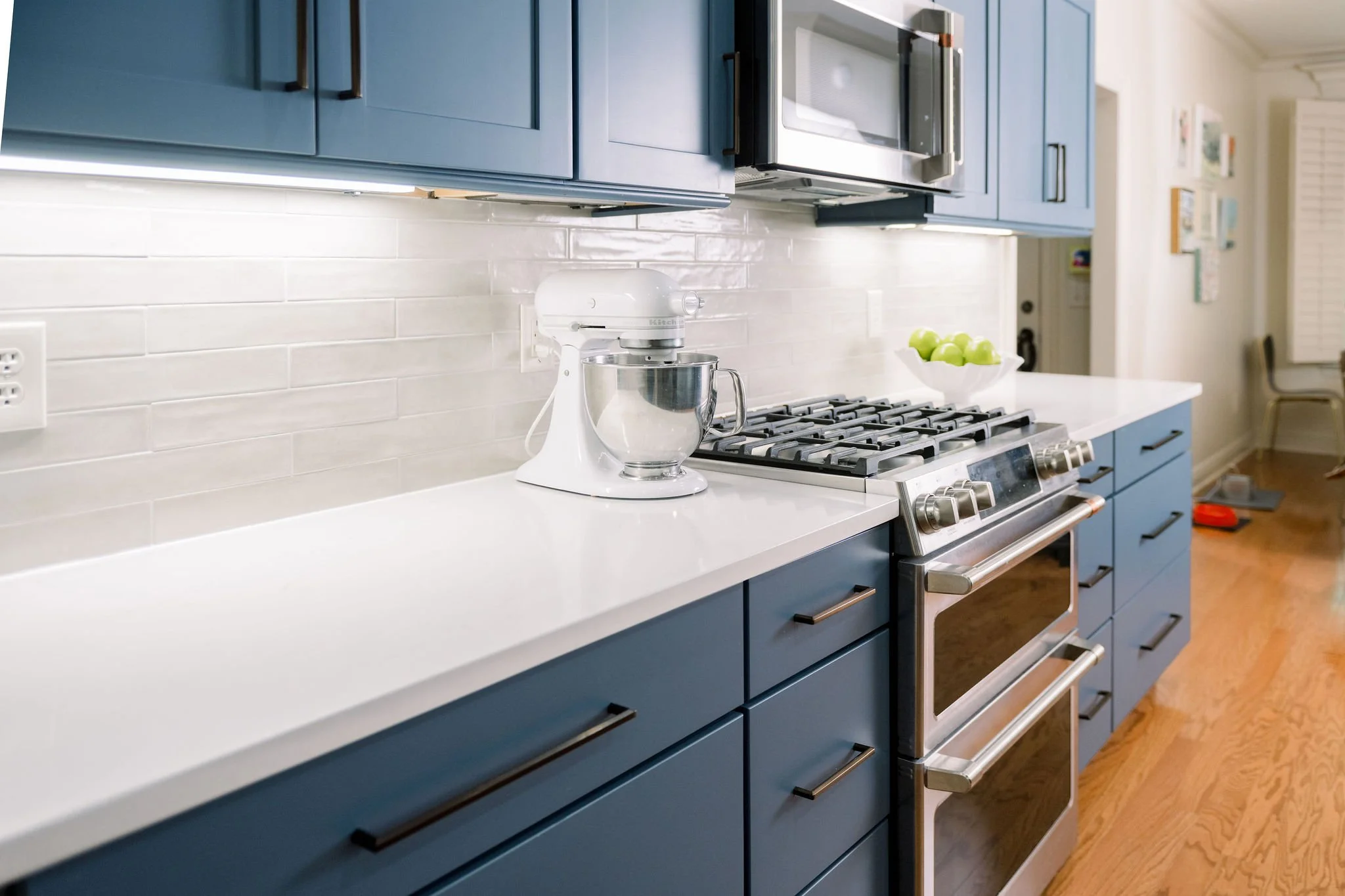 Modern kitchen with blue cabinetry and a white quartz countertop featuring an eased edge, paired with a stainless steel range and clean subway tile backsplash.