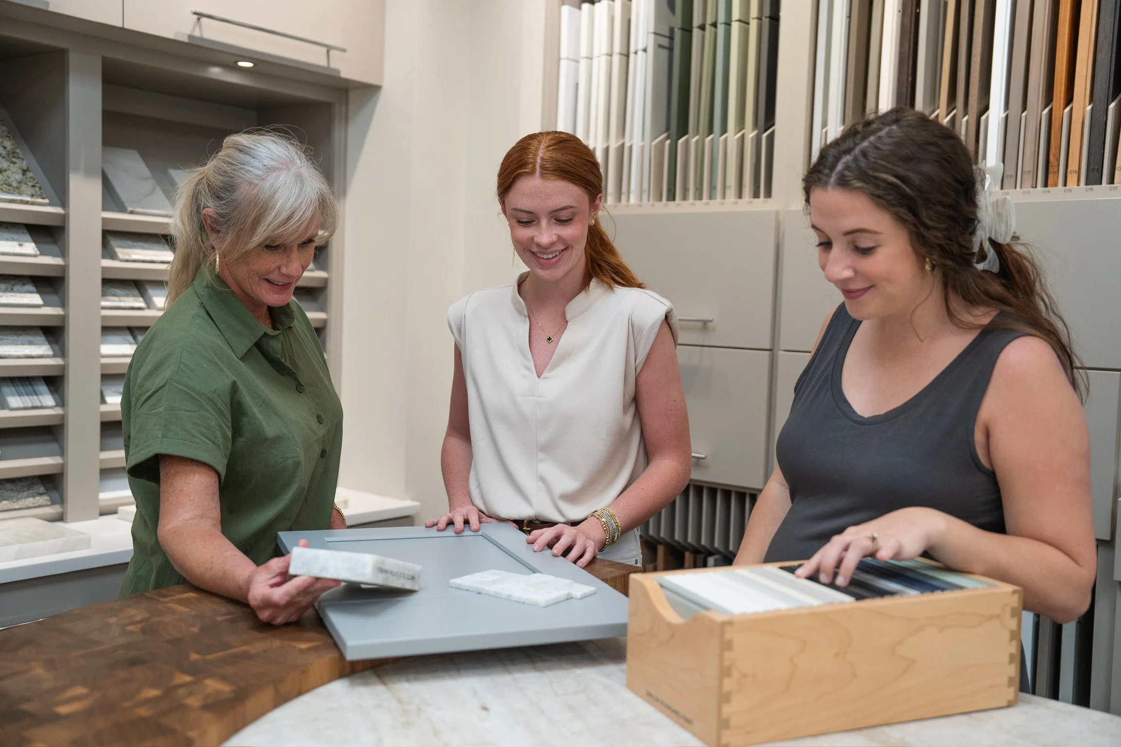 Designers at Toulmin Kitchen & Bath selecting materials in the Tuscaloosa showroom, reviewing cabinetry finishes, tile samples, and design details for a custom project.
