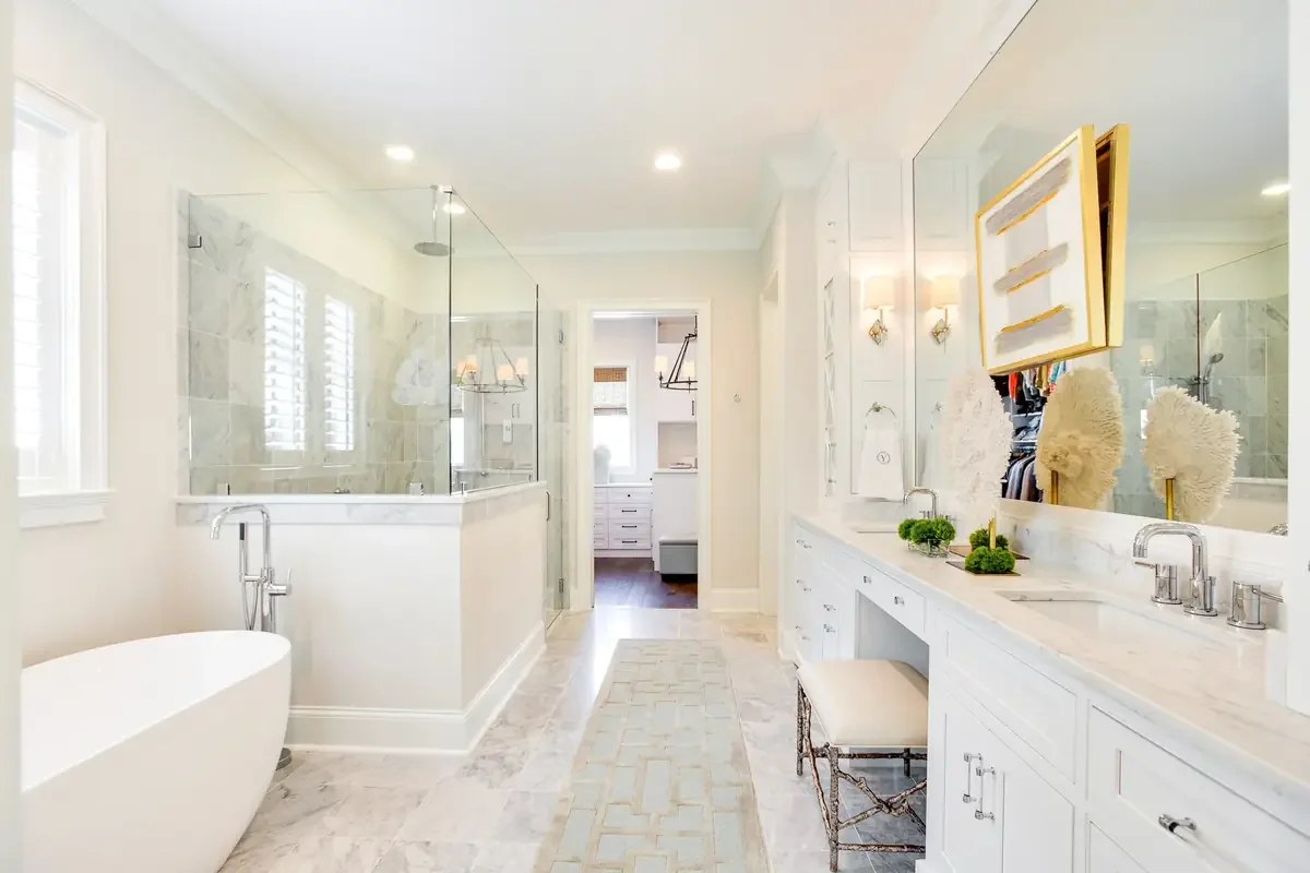 Luxury primary bathroom with custom white cabinetry, marble countertops, freestanding soaking tub, and walk-in shower in a Tuscaloosa custom home.