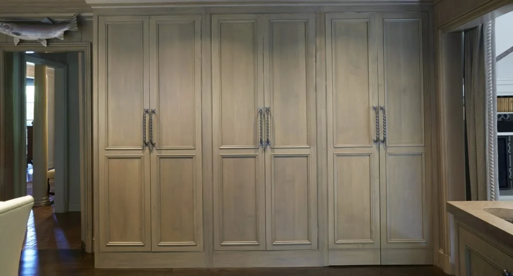 upper cabinet doors feature elongated recessed panels, while the lower sections introduce additional horizontal detailing.