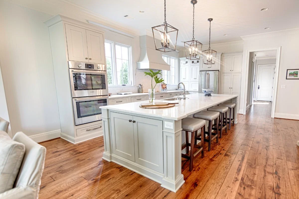 Bright remodeled Tuscaloosa kitchen with a large island, white cabinetry, and pendant lighting.