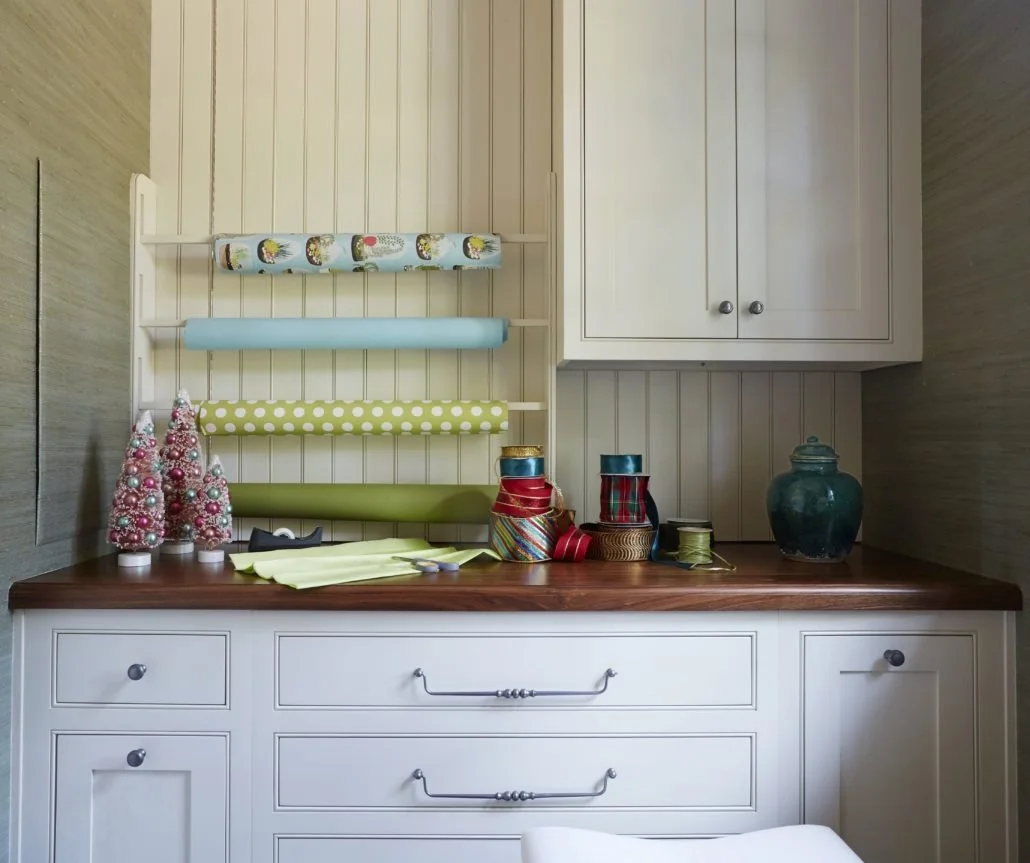 Custom cabinetry creates an organized wrapping and craft station with deep drawers, countertop workspace, and built-in paper storage.