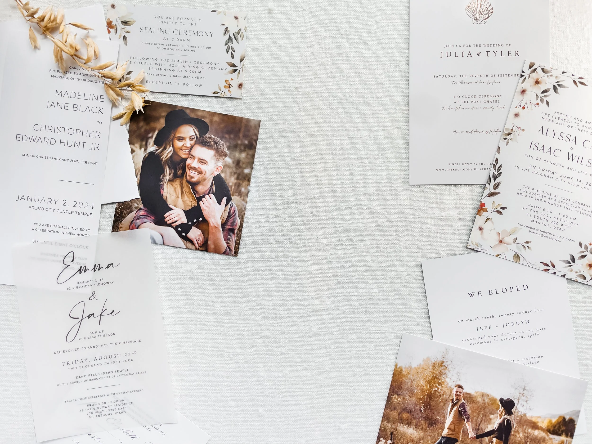 A collection of wedding invitations and announcements arranged artistically on a white textured background. The invitations feature elegant designs with floral motifs and calligraphy. Among them is a photo of a smiling couple embracing and another photo of a couple walking hand-in-hand outdoors.