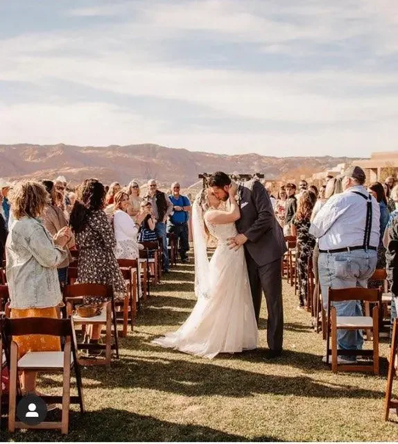 Wedding ceremony at The Ledges Weddings & Events in St. George, Utah with red rock cliffs and golf course views. - St George Wedding Invitations
