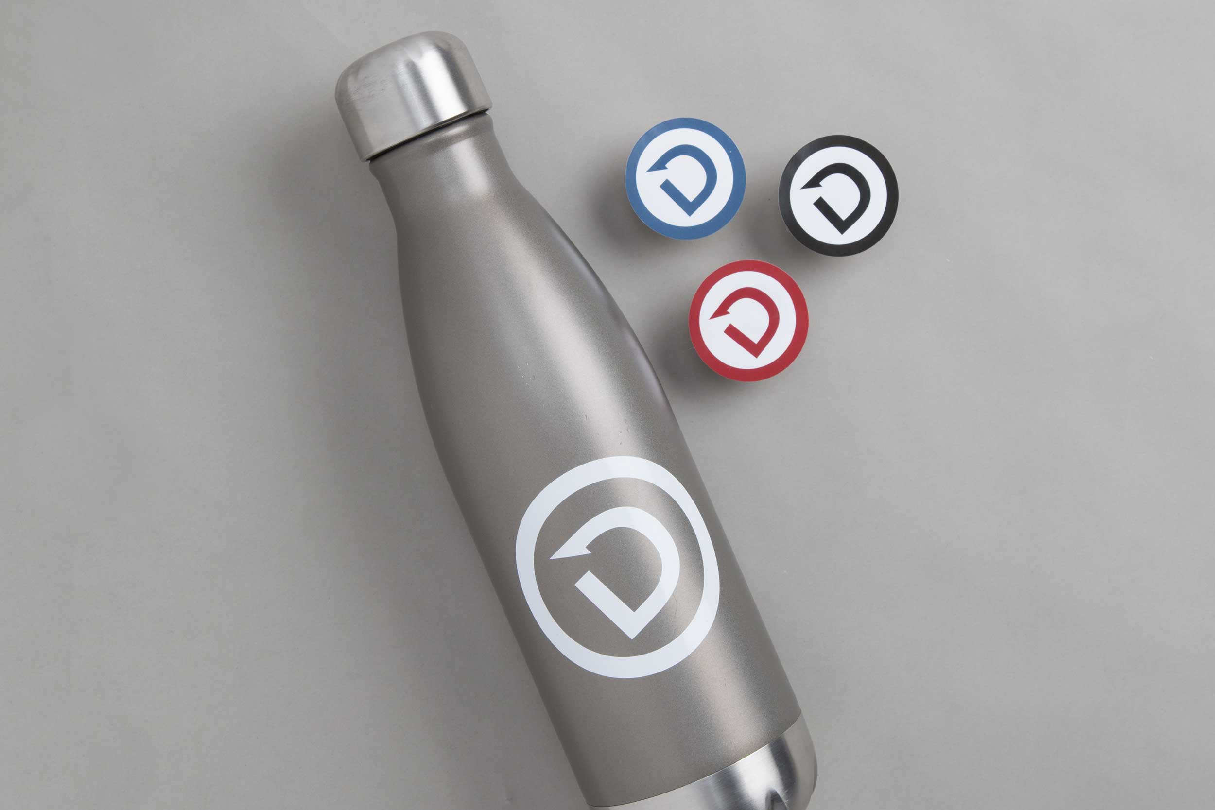 A water bottle and stickers with the Dare to Detour icon.