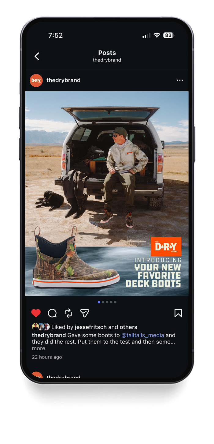Instagram post from the drybrand showing a person sitting on the back of a vehicle outdoors, a black dog lying nearby, and an advertisement for new deck boots with a camouflage design.