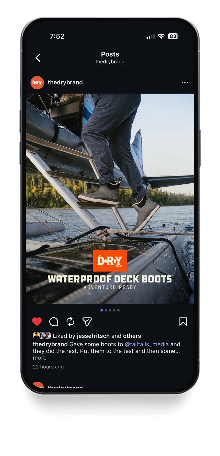 A person is stepping onto a boat using waterproof deck boots, with water and trees in the background.