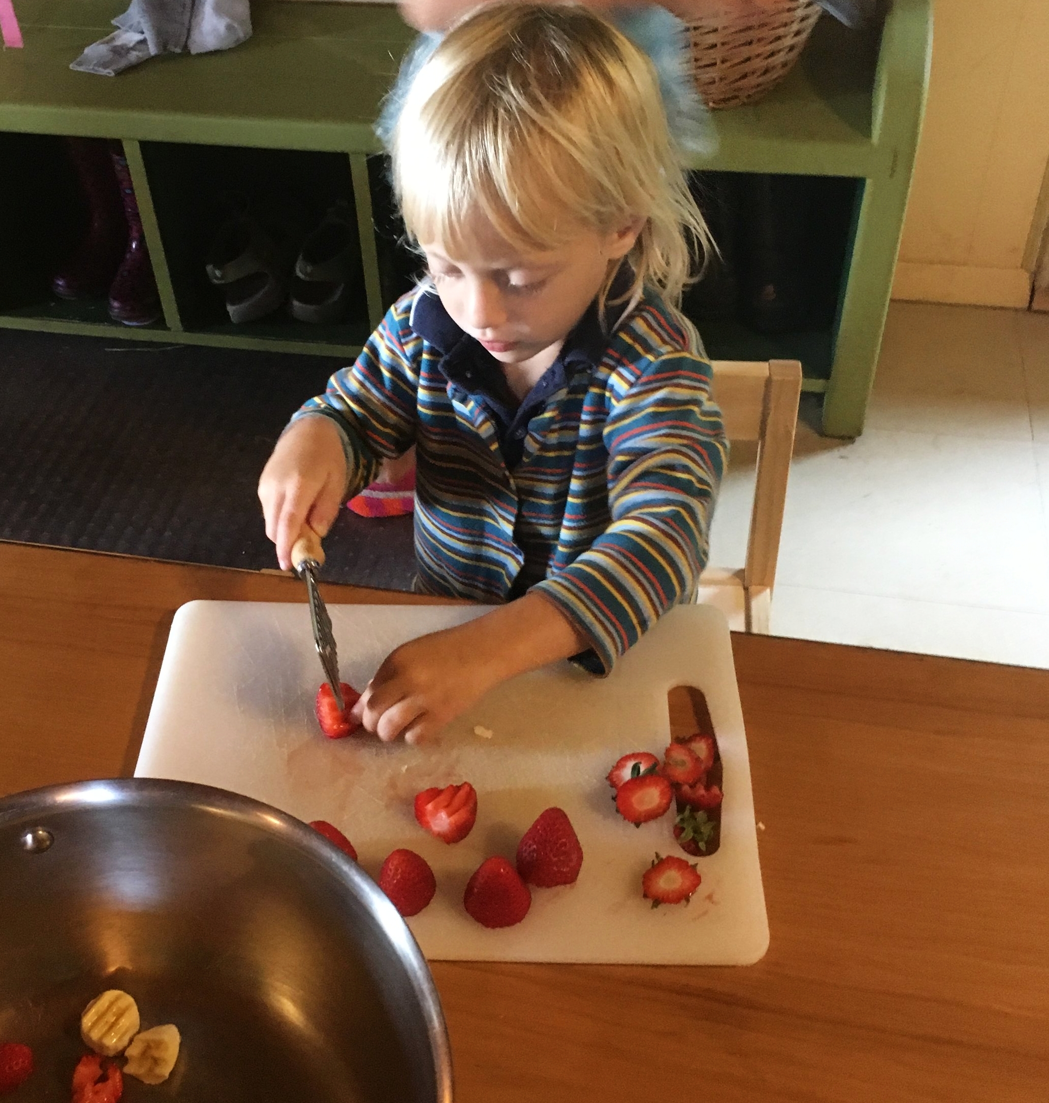 On 'Oatmeal Day', a child chops fresh strawberries from our gardens as a topping