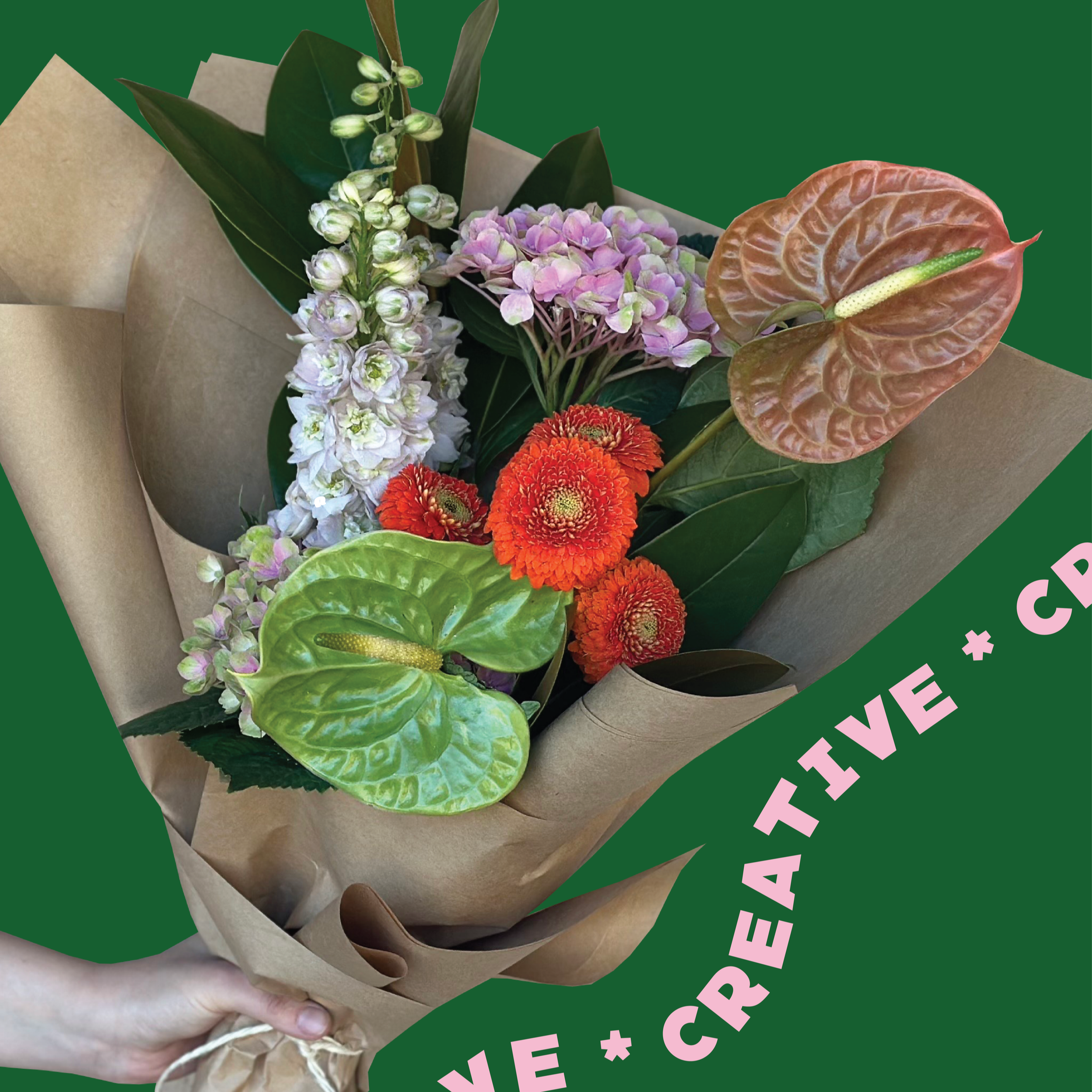 Creative florist's choice bouquet featuring vibrant red and purple flowers, ornamental anthuriums and lush greenery.