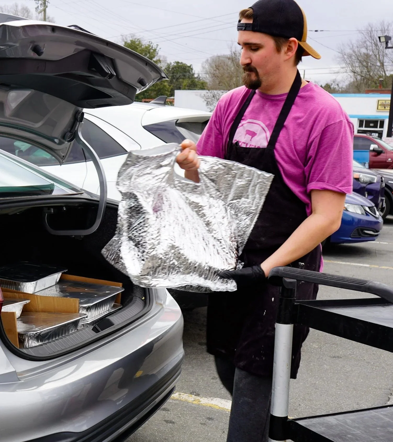 A Smokehouse at Steve's employee assisting a customer in loading her car up with the bulk catering order she is picking up.