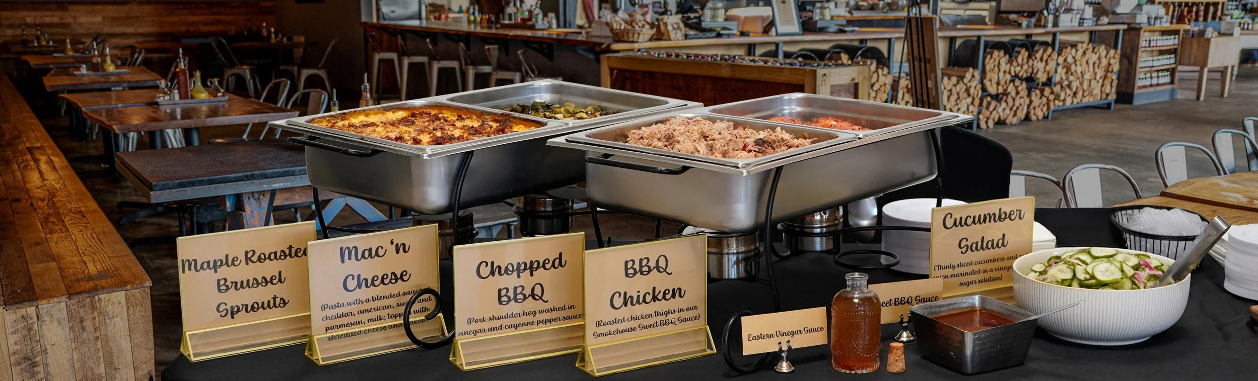 Catering from Smokehouse at Steve's, chafing dishes set with mac and cheese, chopped BBQ, BBQ chicken, cucumber salad, and BBQ sauces.