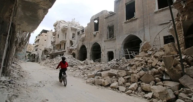 A boy rides his bicycle amid ruins in war-torn Aleppo (Reuters Photo)