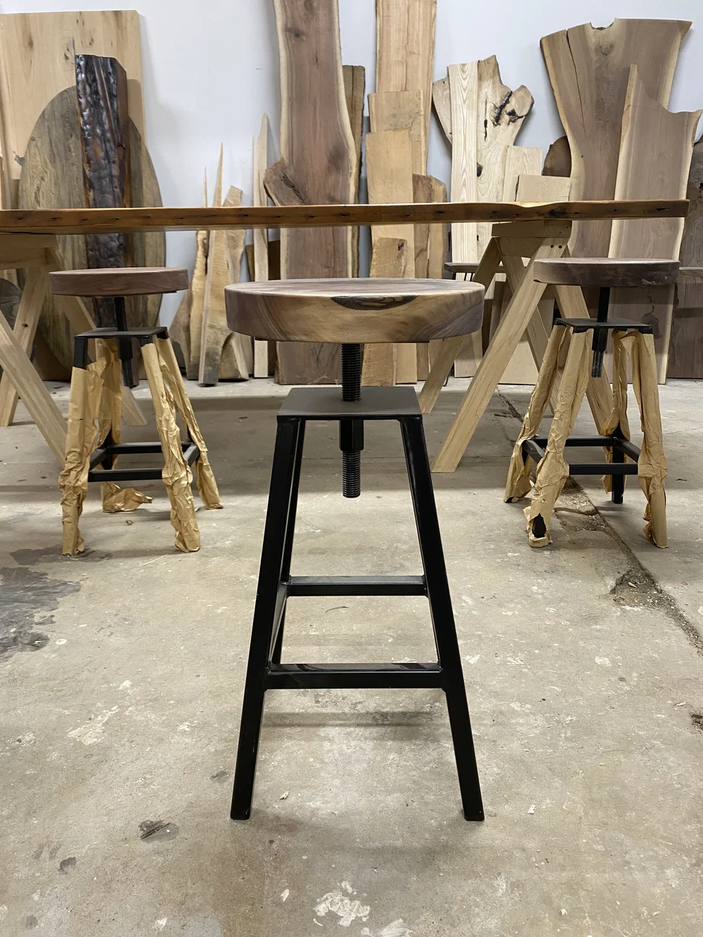 side view of custom made high top stools with black walnut wooden seats and black metal base.