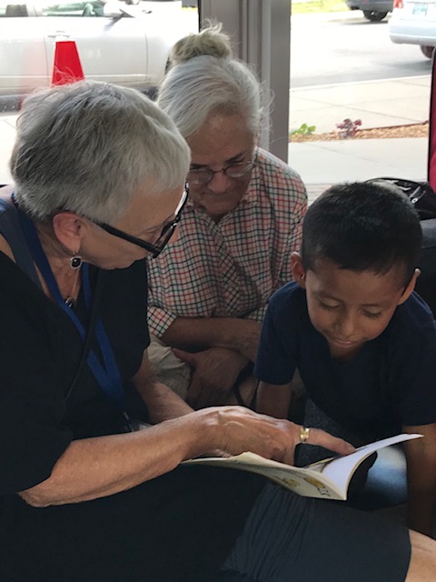 Two Christ Church Cathedral parishioners reading to a child at the bus station.