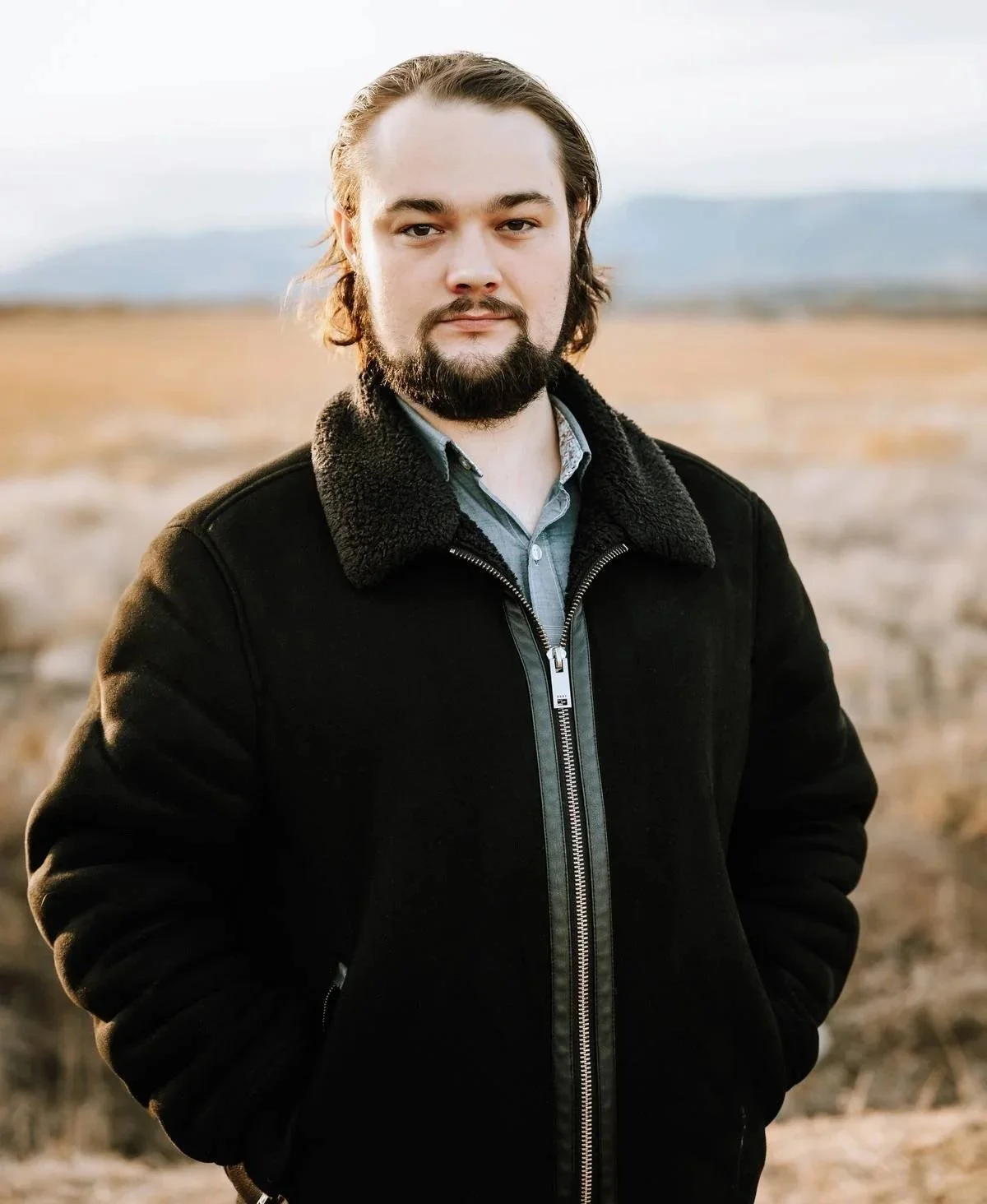 Person standing by the ocean wearing a striped shirt, with a calm sea and horizon in the background.