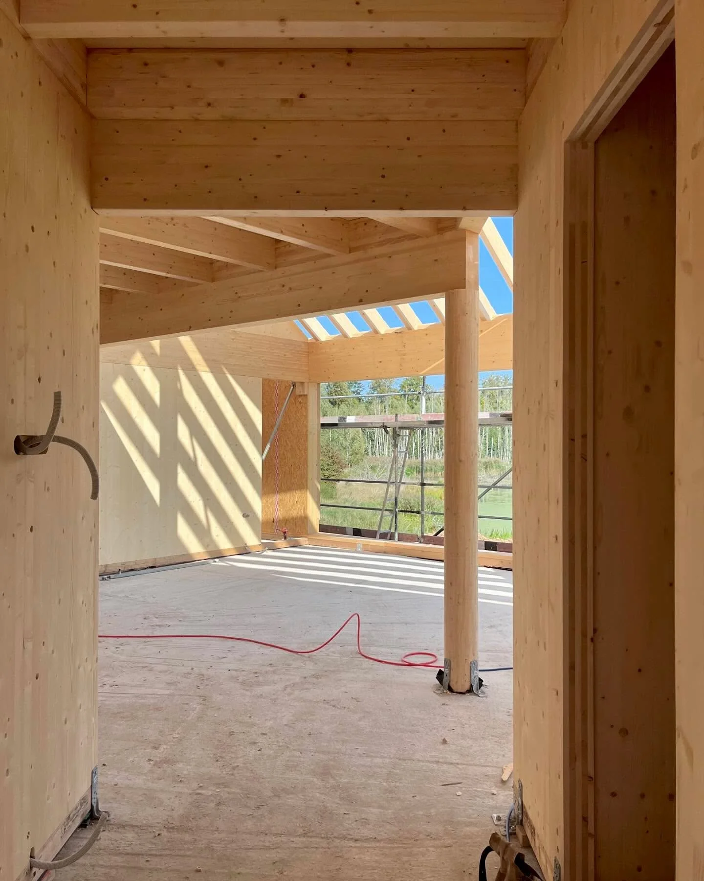 A few more shots of progress last week at the House in the Pasłęka River Valley.

The cranked form of the house creates a living room with expansive views of the flooded landscape.

This generous space is given intimacy by the mezzanine above, which 
