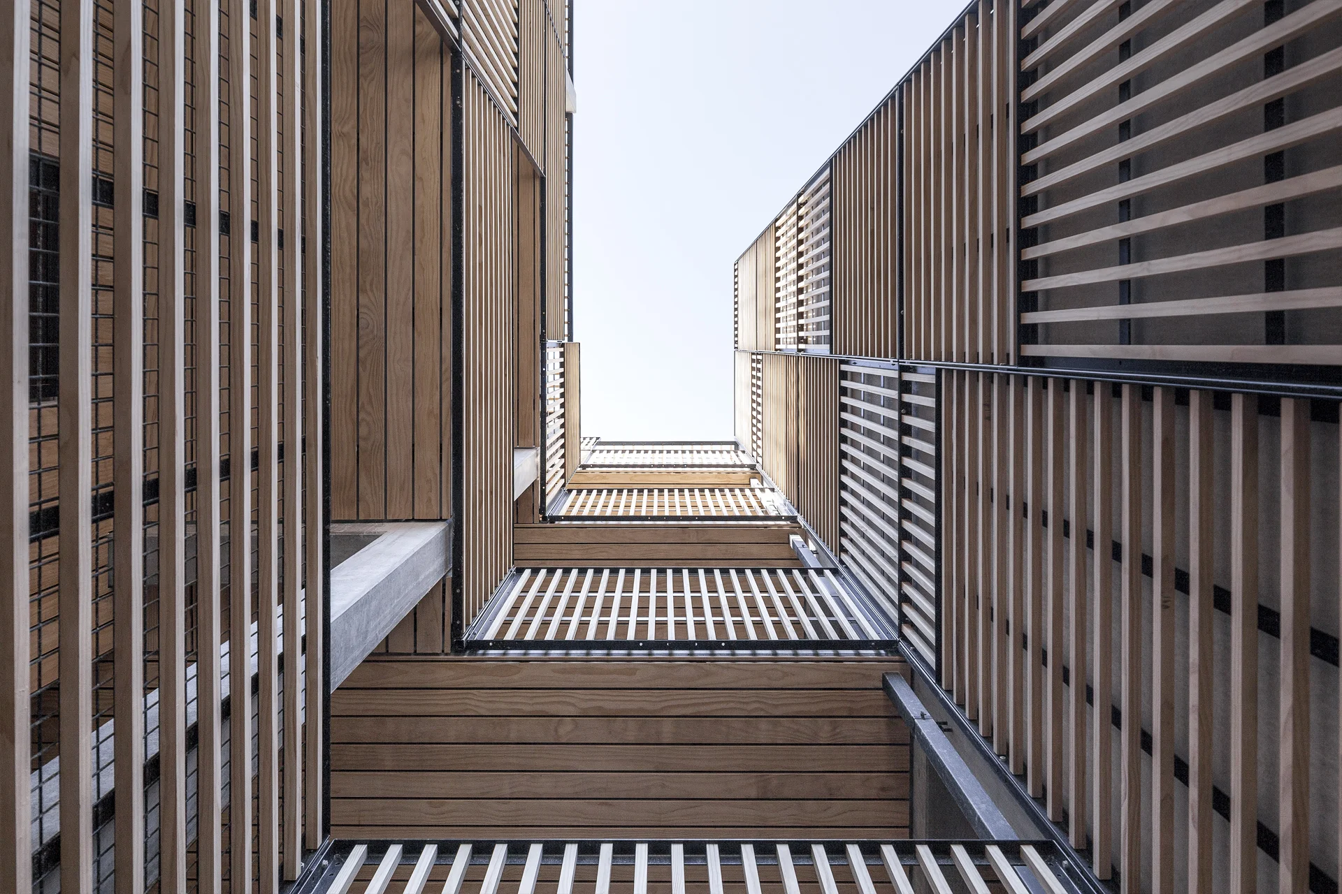 Looking up in the inner courtyard reveals the beautiful variation in the patchwork facade up close. Contrast between cold concrete/warm wood - bright color tones and black metal.