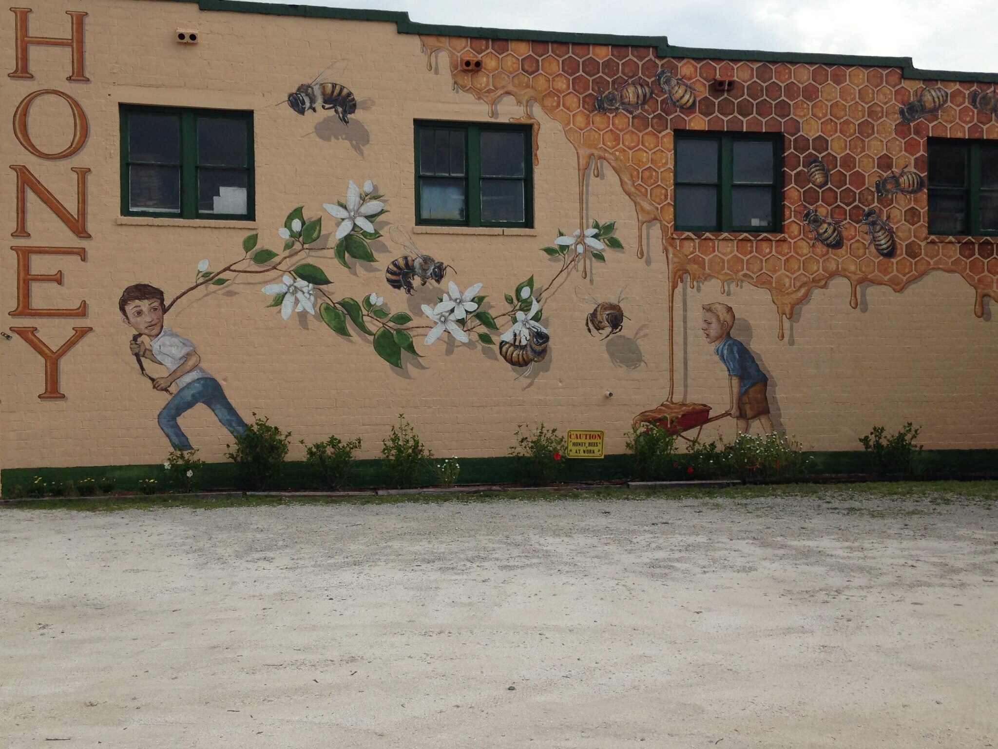 Mural of children carrying honey and running among bees and flowers