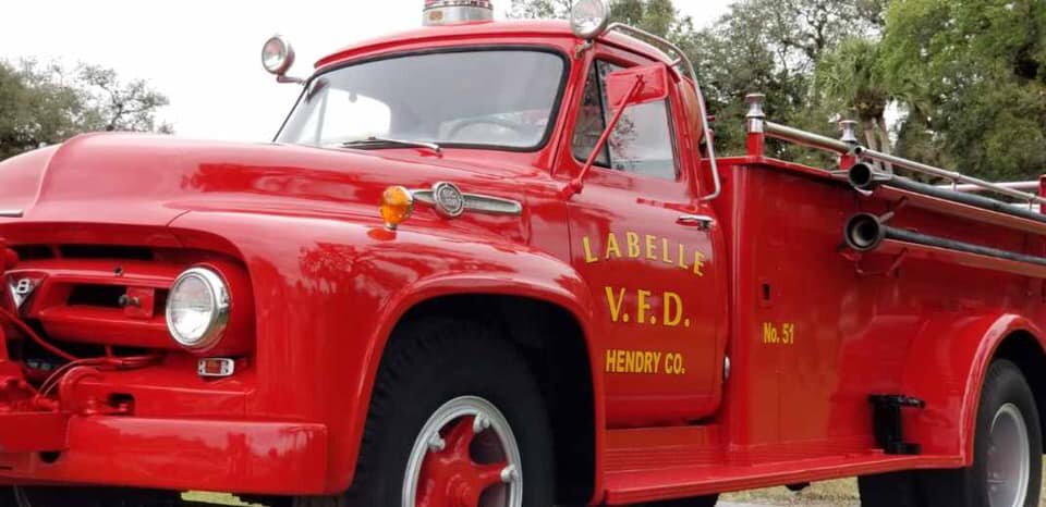 Red 1953 Ford fire truck in front of trees