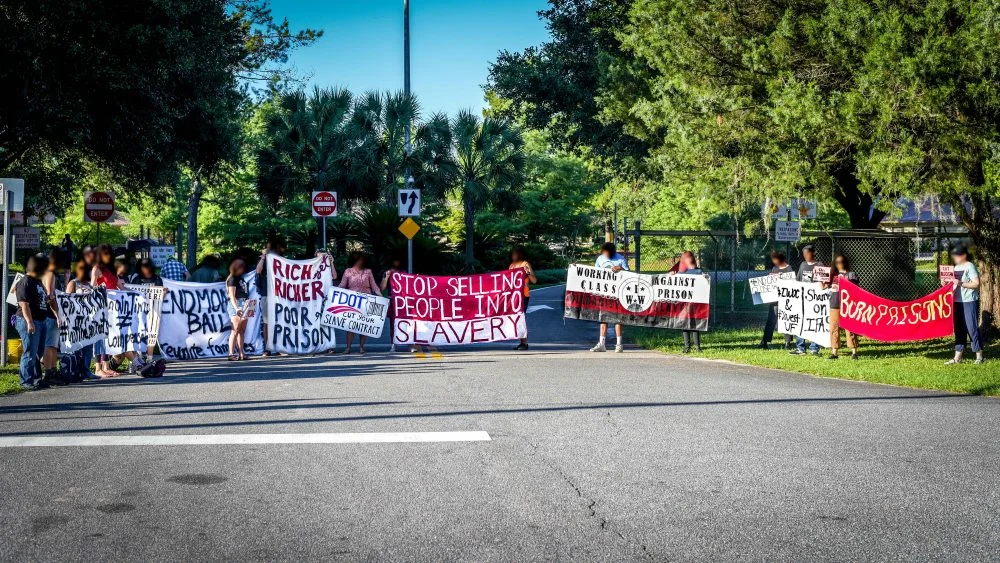 Gainesville, FL — A demonstration began at 7:30 a.m. at the Florida Department of Transportation (FDOT) offices, located at 5007 NE 39th Ave, disrupting the activity of Department of Corrections (FDOC) which has a $19 million contract to lease out prisoners as unpaid slaves to do road work for the State. More details here . Photo by Fight Toxic Prisons
