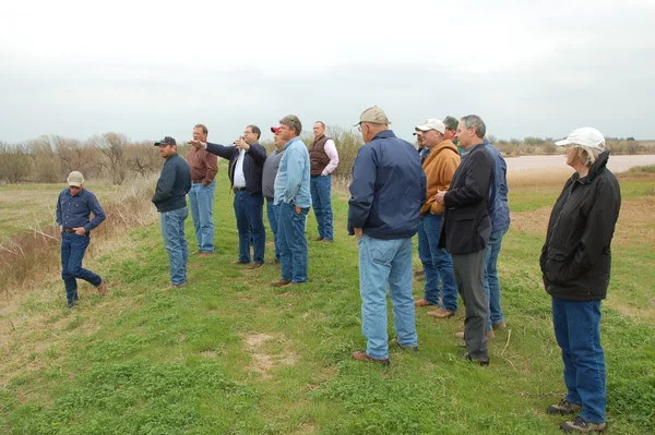 Larry Caldwell, Oklahoma Conservation Commission Watershed Specialist, with arms outstretched, explains the functions of a watershed flood control dam. This photo was taken a few years ago in Garfield County at one of the dams in the Upper Black Bear Creek Watershed.