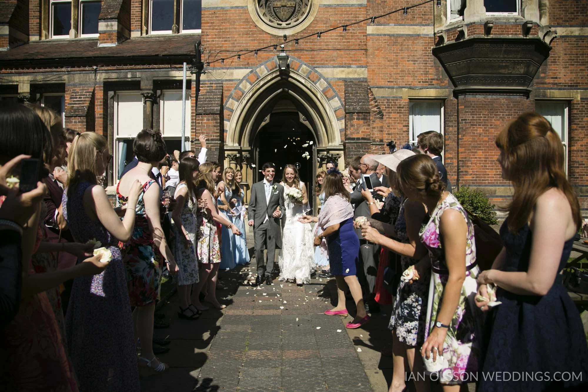 Arriving at the Cambridge Union through a confetti tunnel for their beautiful summer wedding reception 