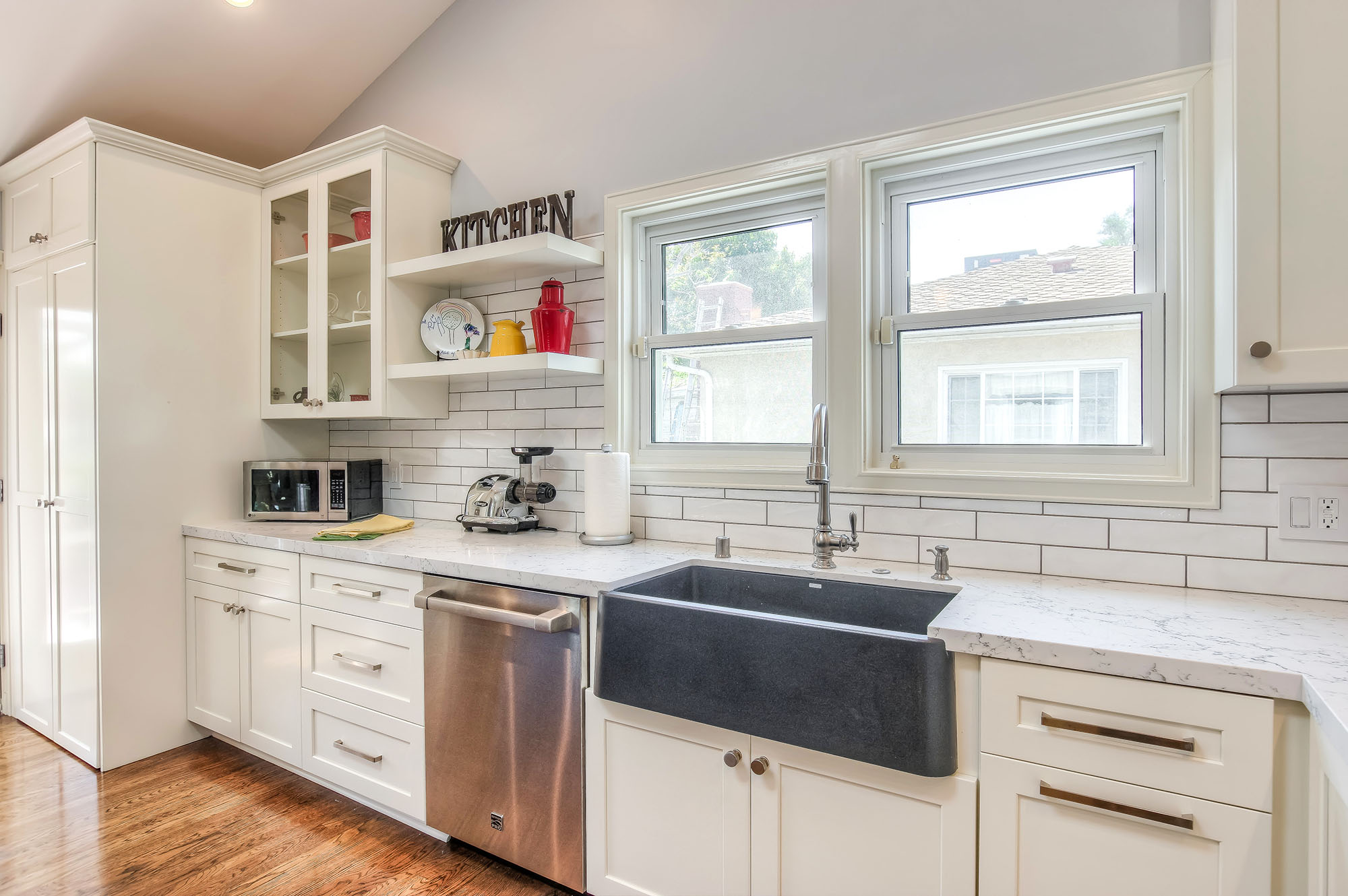  The bright and colorful kitchen features custom built shaker cabinets, Caesarstone quartz countertops, Bosch appliances and farmhouse style Blanco sink. 