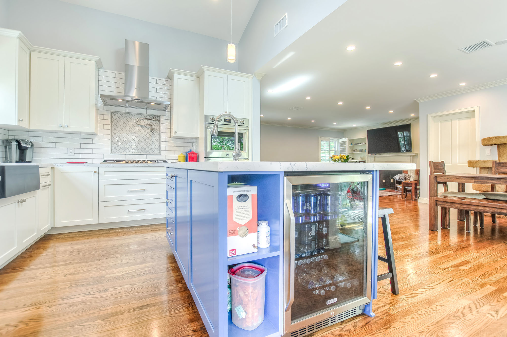  To add a focal point and a pop of color to the all-white bright kitchen we created a custom island in blue with an extra sink, storage space and a wine cooler. 