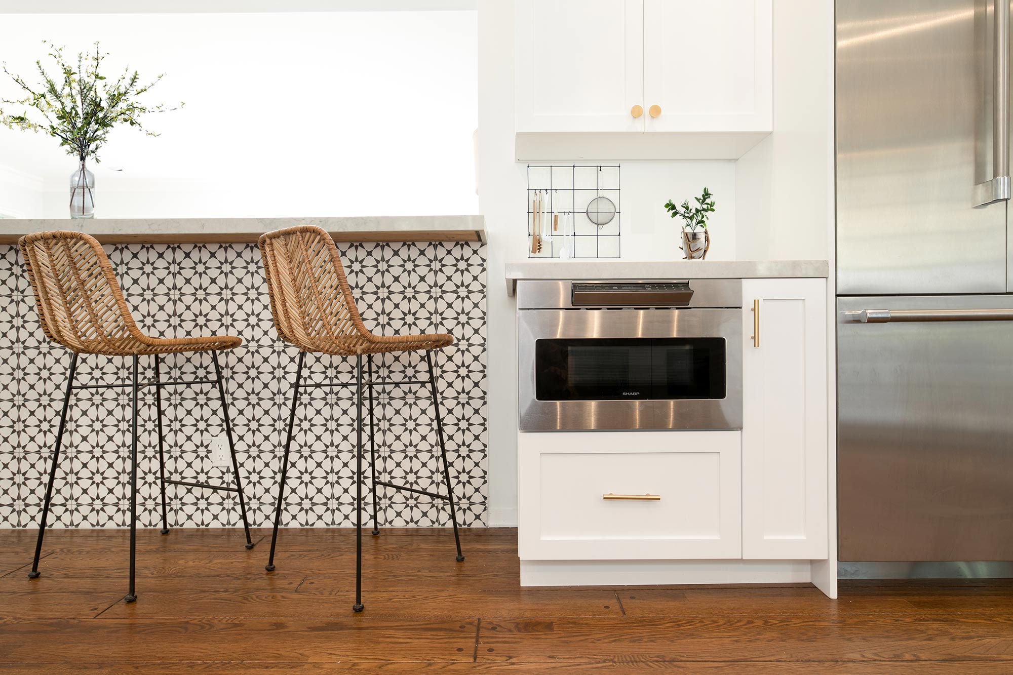  The new open kitchen features custom-made white shaker cabinets with gold pulls and knobs, black fixtures, new hardwood floors, white 5"X5" ceramic tile backsplash, Caesarstone Noble Grey countertops, breakfast bar with pattern cement tile detail, T